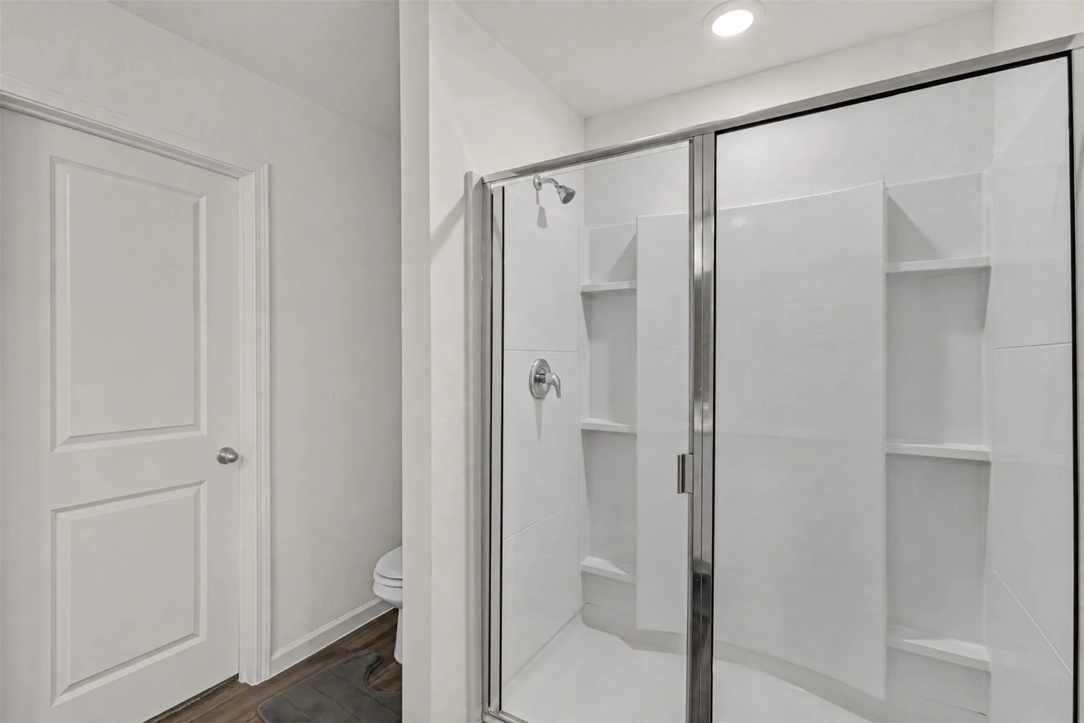 Walk-in shower with sliding glass door and integrated shelving