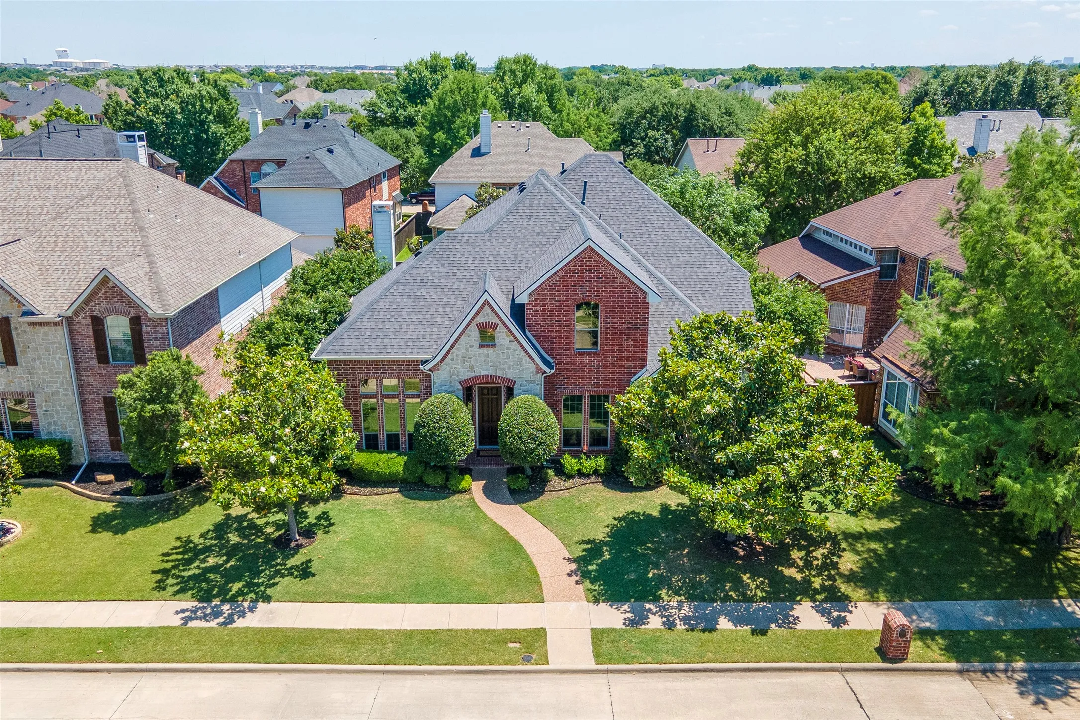Framed by mature magnolia trees and manicured landscaping, this stately brick-and-stone elevation creates a warm first impression from the moment you arrive.