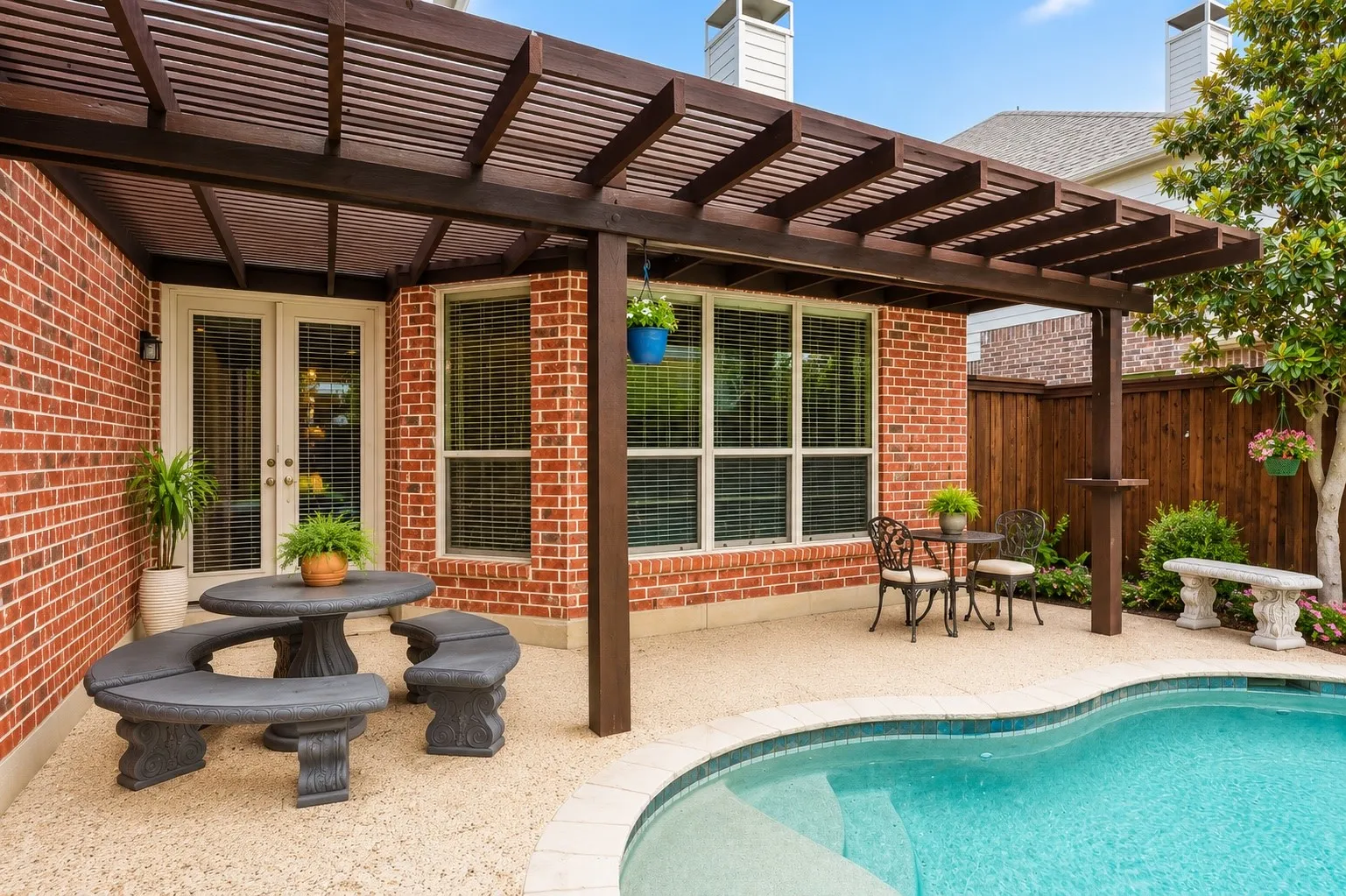 Framed by rich brick accents and architectural beams, the covered outdoor living space blends comfort and character just steps from the water’s edge.