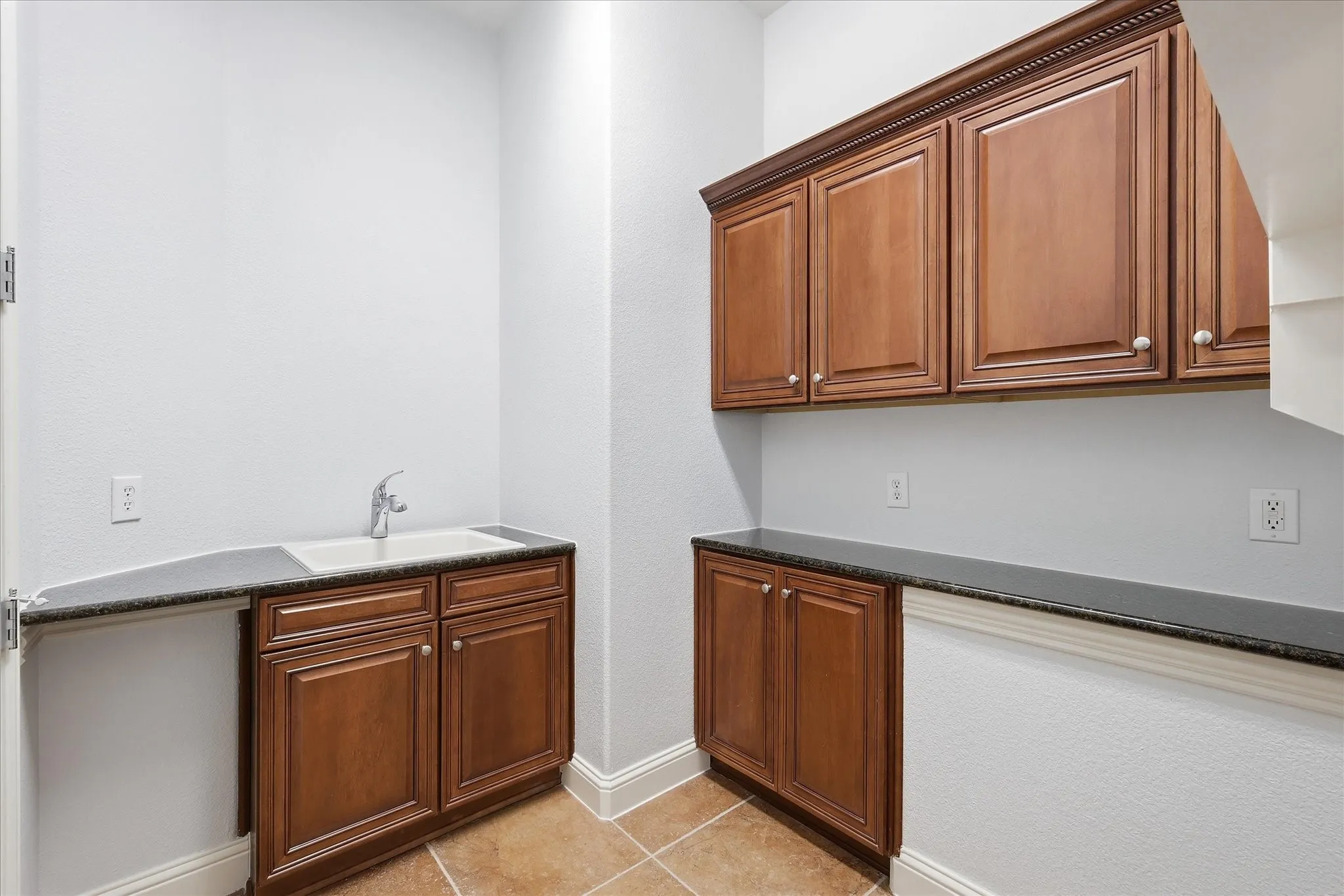 Sink, cabinets, and countertop included in  the laundry room.