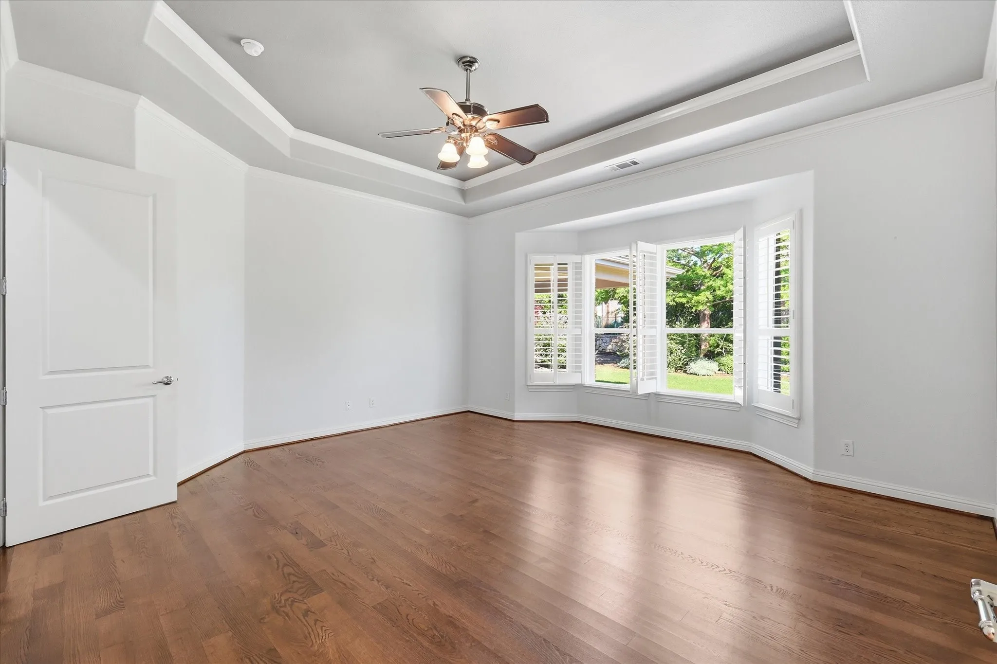 Lovely primary bedroom with windows overlooking the backyard and tray ceilings.