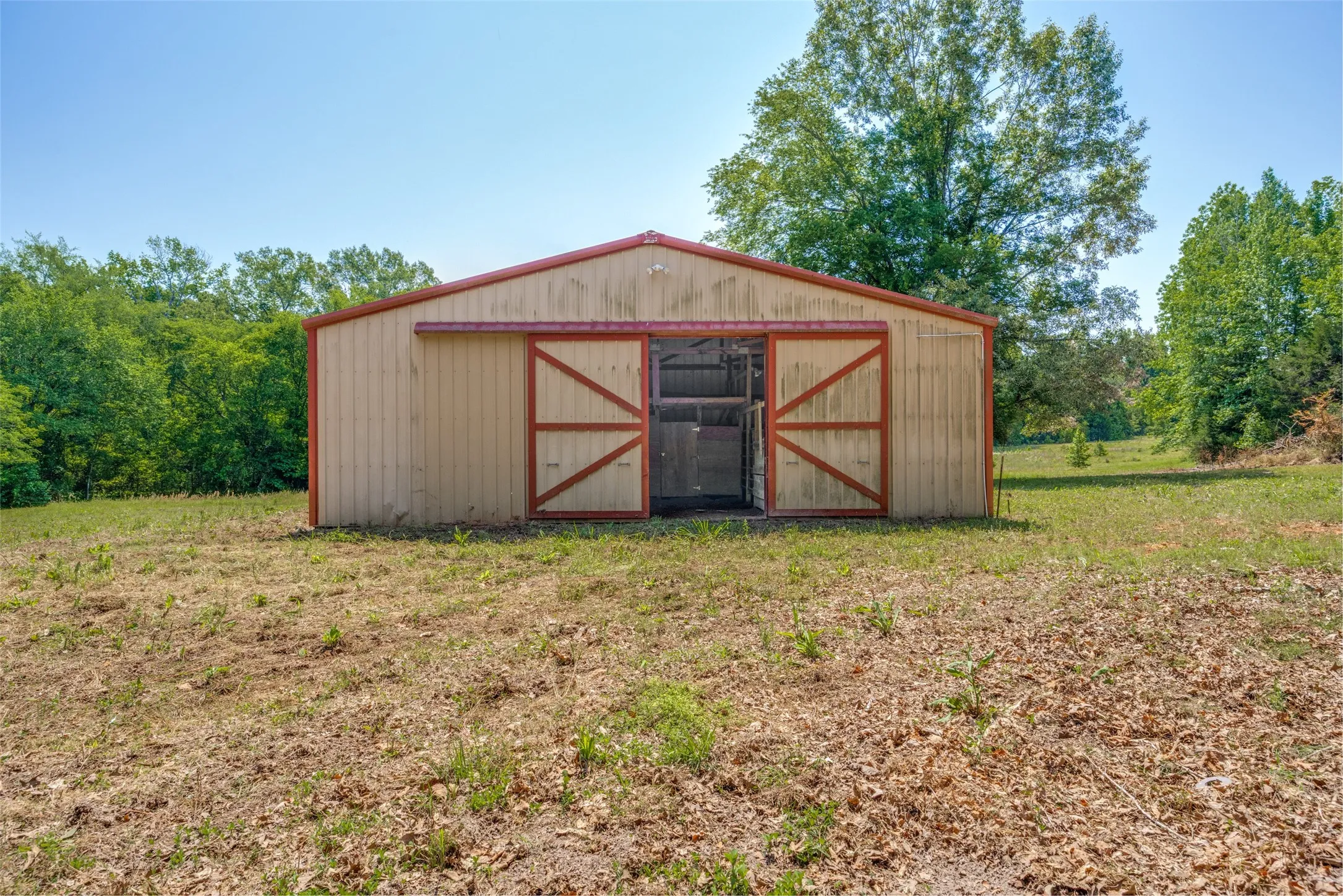 Barn structure featuring a metal roof and cream-colored siding with red trim