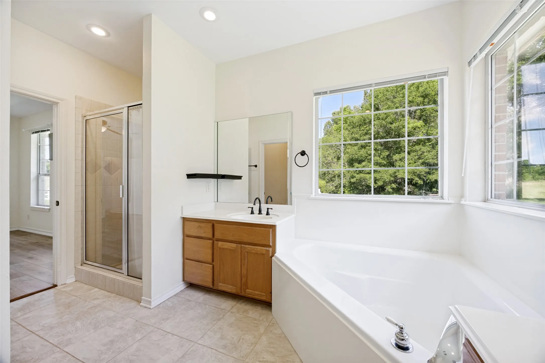 Bathroom featuring a spacious soaking tub, large grid windows, and a glass-enclosed shower