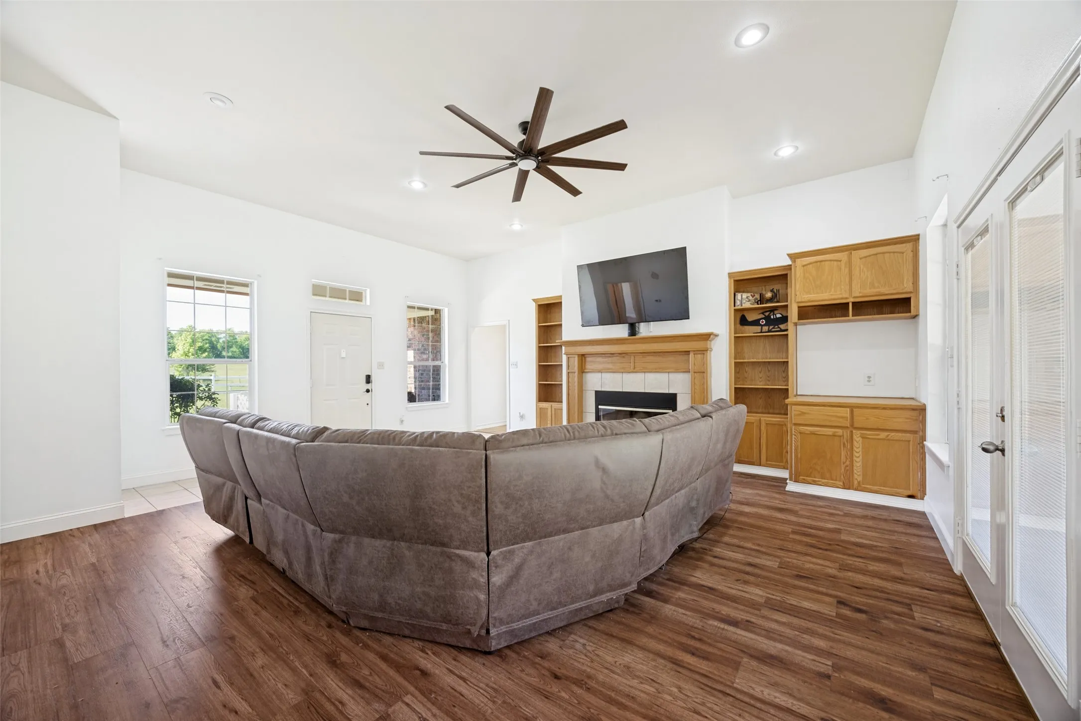 Spacious living area featuring wood-finish flooring, a ceiling fan, recessed lighting, and white walls