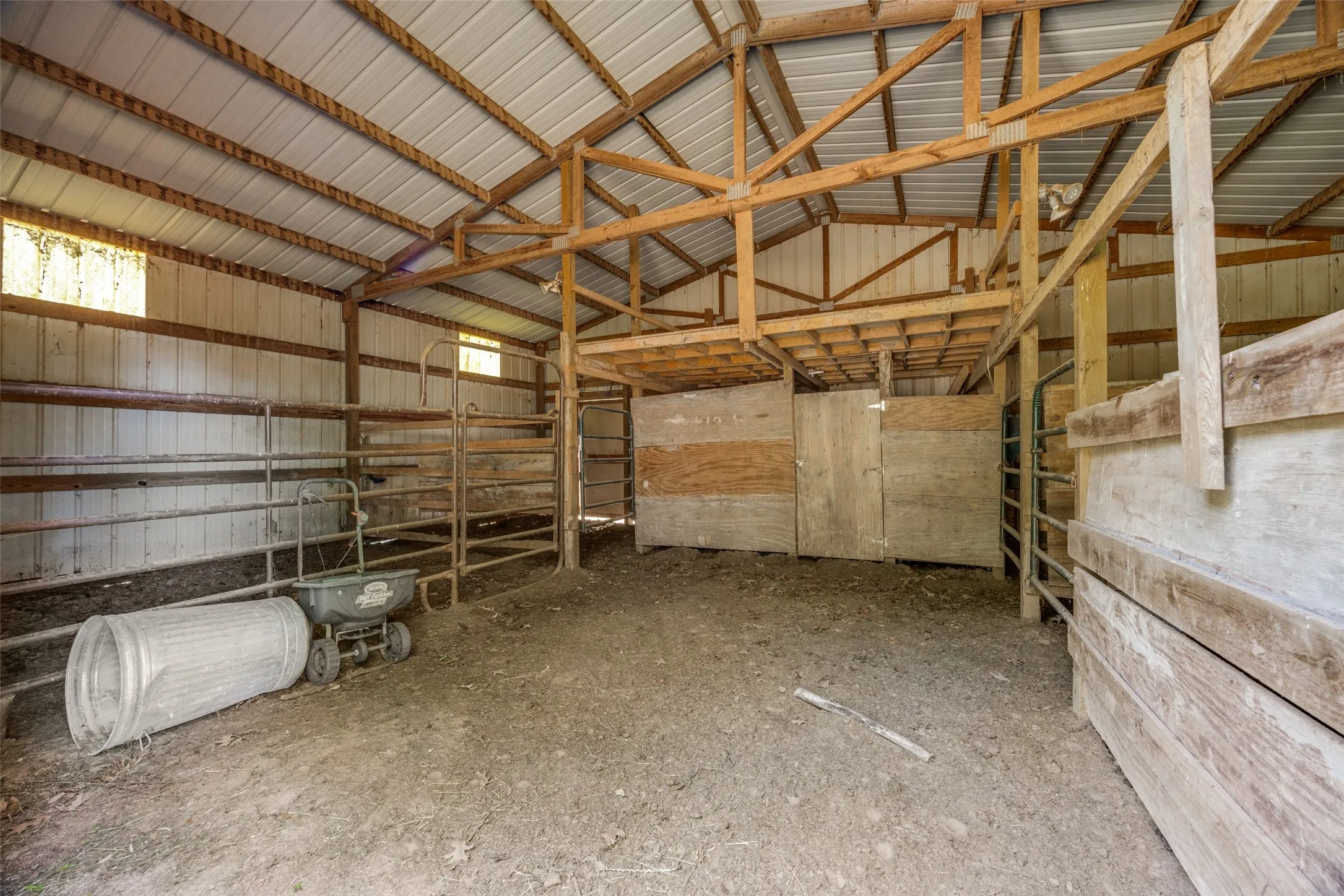 Open-concept barn interior featuring exposed wooden rafters and a metal roof