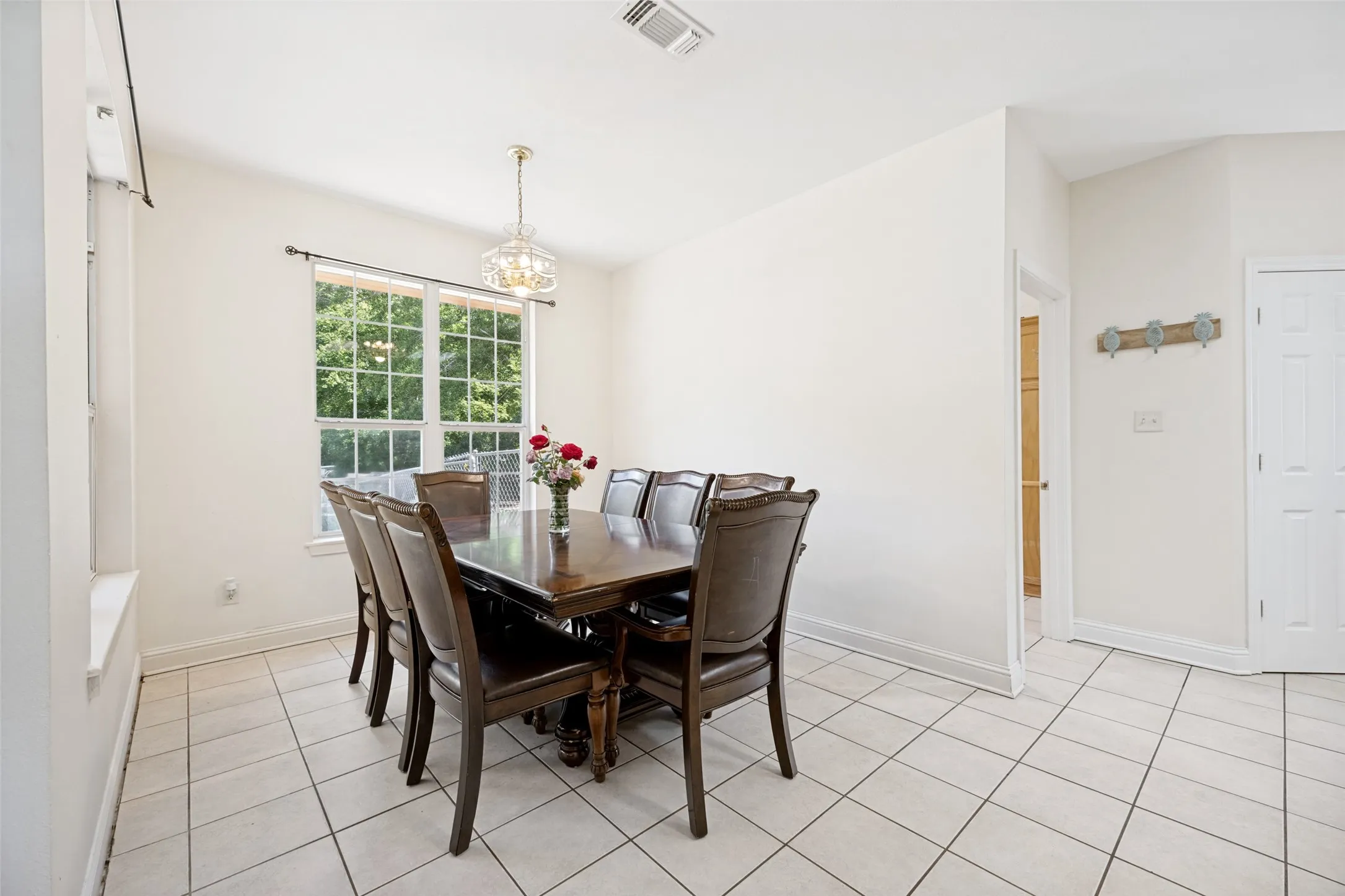 Spacious dining area featuring neutral tile flooring, a multi-pane window, and a decorative pendant light fixture