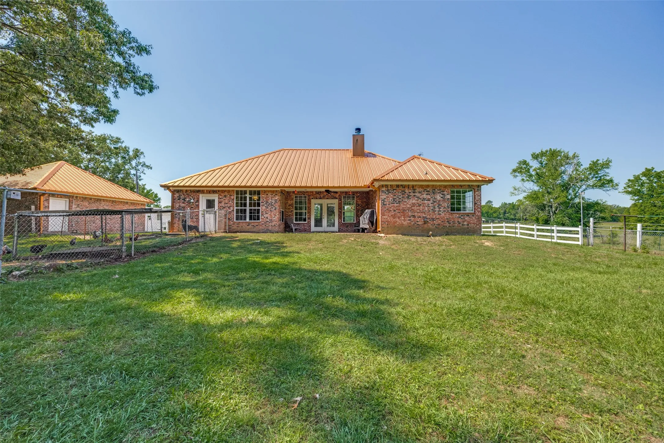 Brick exterior with a metal roof and an expansive lawn