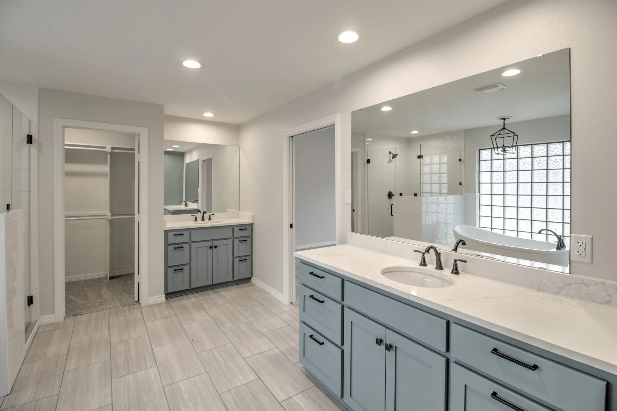 Large Bathroom, with two walk in closets, quartz countertops, tile floors, 2 separate vanity areas with sinks.