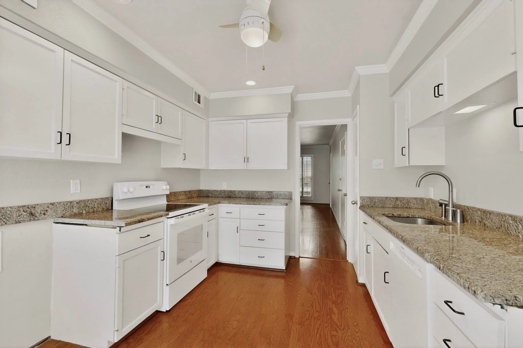 Kitchen featuring white cabinetry, granite-finish countertops, stainless steel sink, white electric range, and wood-finish flooring
