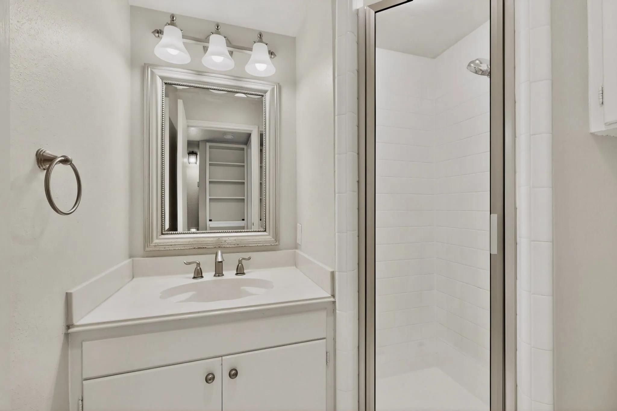 Bathroom featuring a white vanity with integrated sink, brushed nickel faucet, and framed mirror