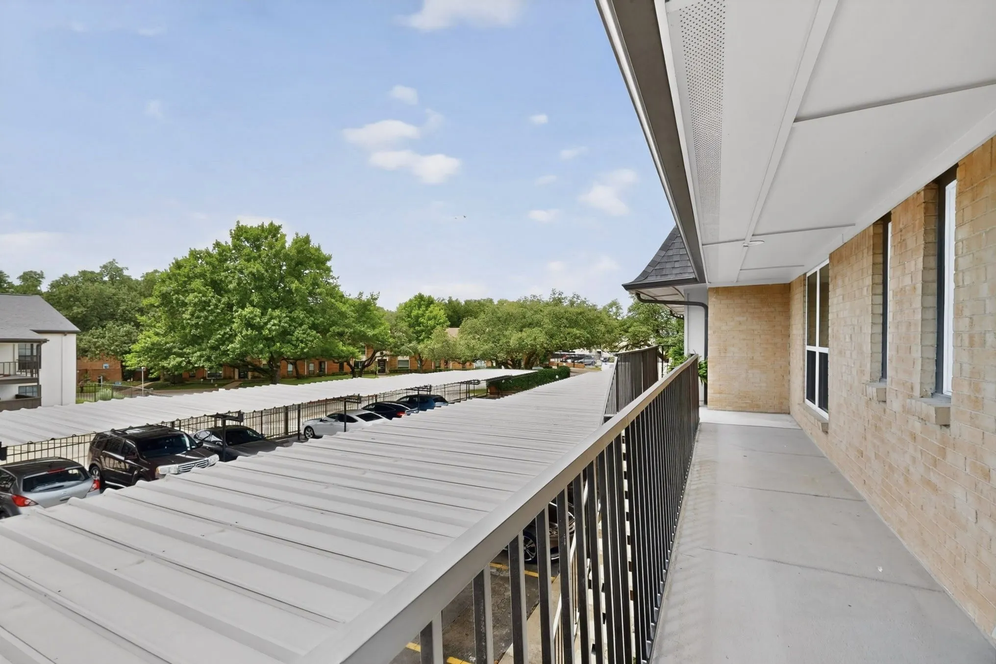 Exterior balcony featuring a black metal railing and light brick facade