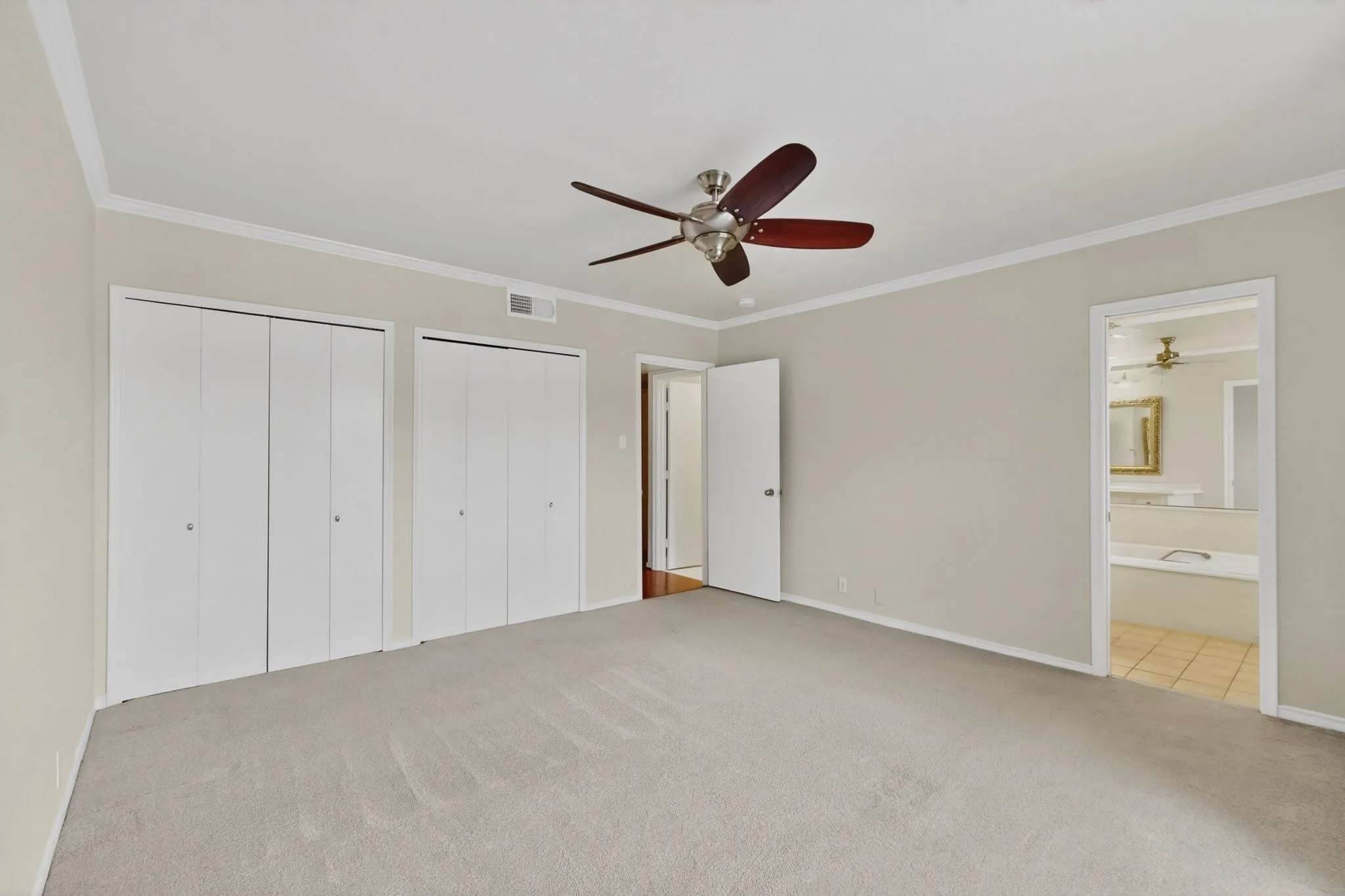 Carpeted room featuring crown molding, neutral wall paint, bi-fold closet doors, and a ceiling fan with light