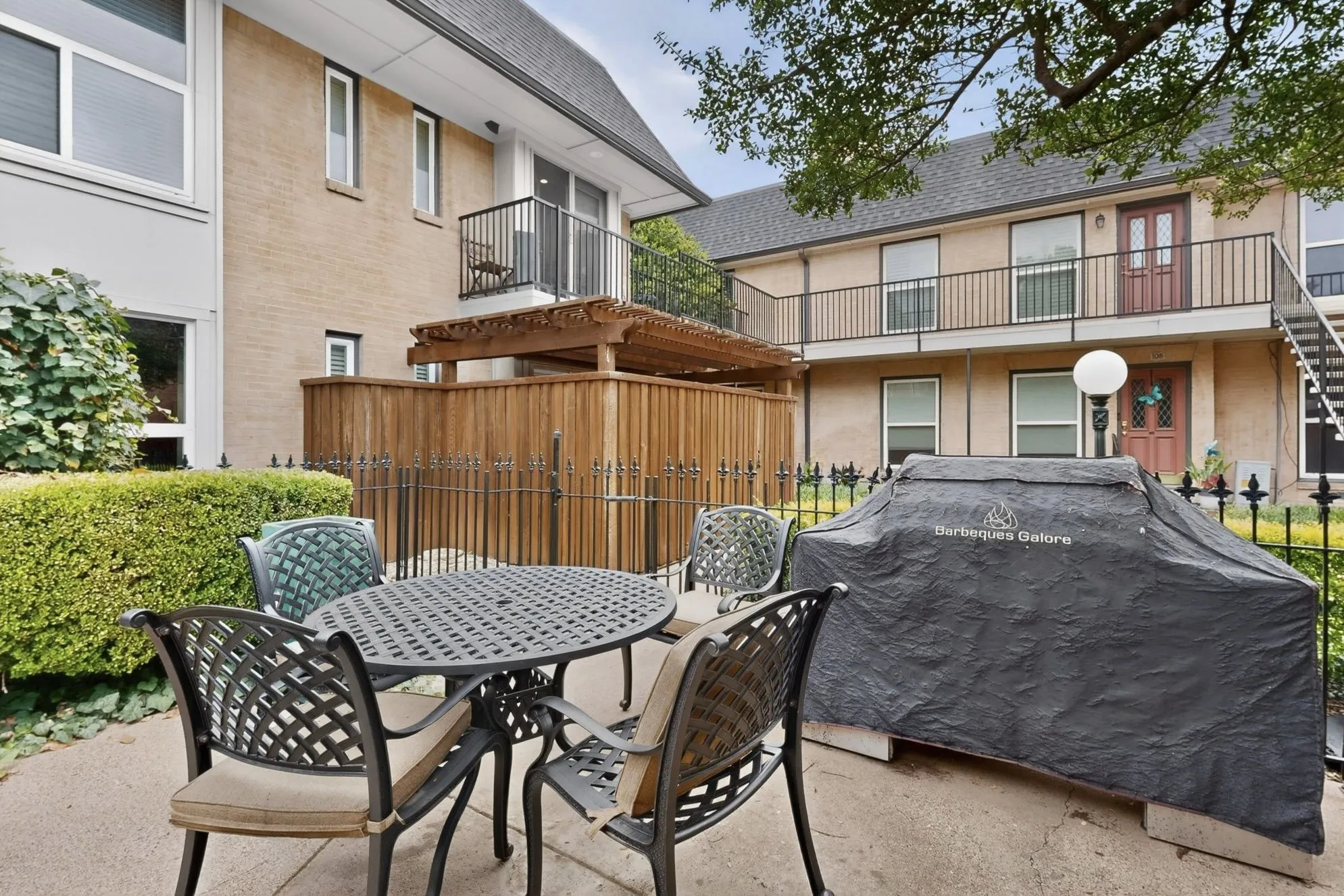 Private courtyard patio featuring a wooden fence enclosure and an iron railing