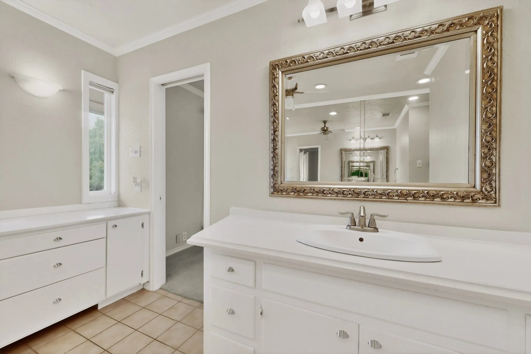 Bathroom featuring a single vanity with an integrated sink, brushed nickel faucet, and a large ornate framed mirror