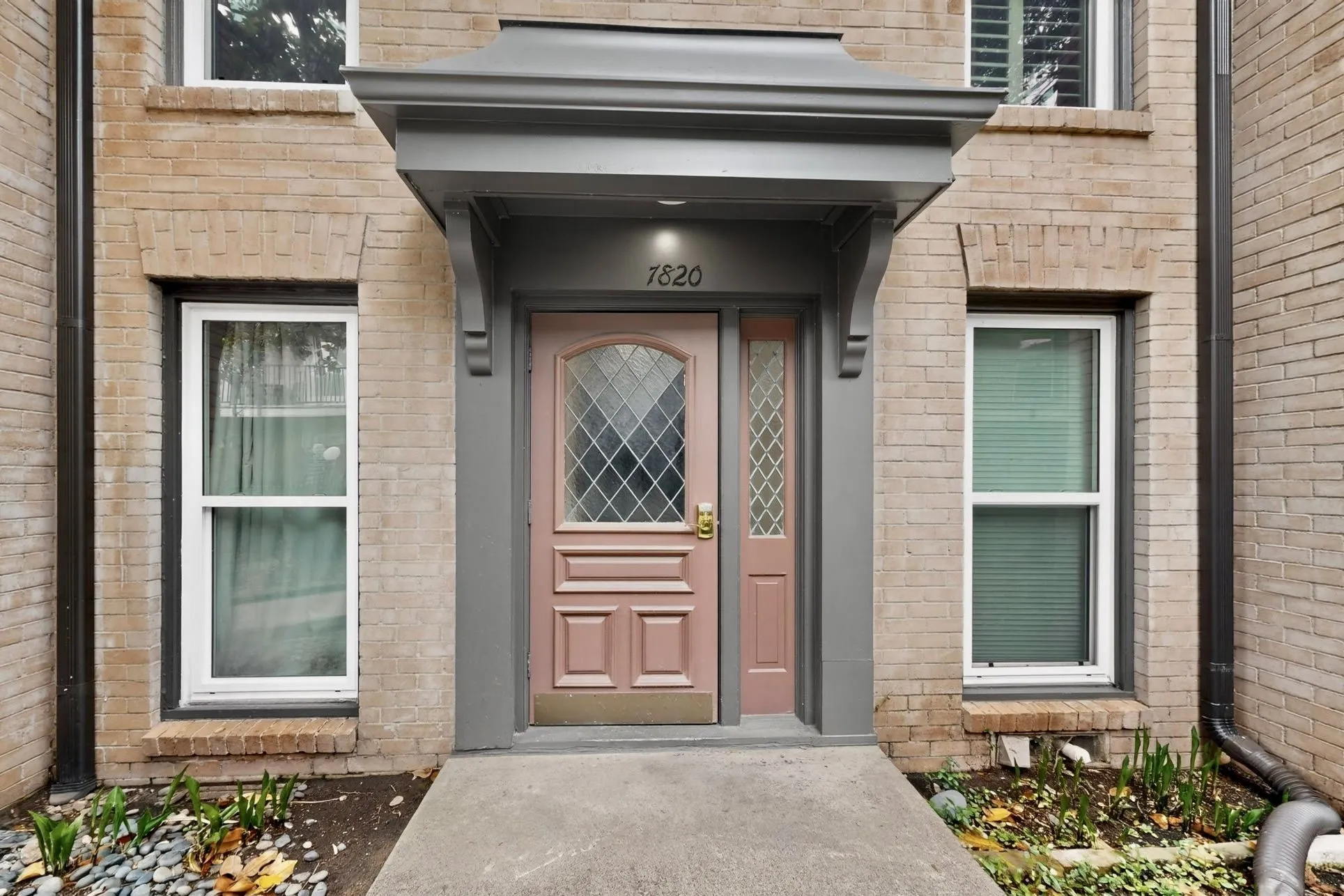 Brick exterior featuring a covered entry, decorative front door with diamond-patterned glass, and an adjacent sidelight