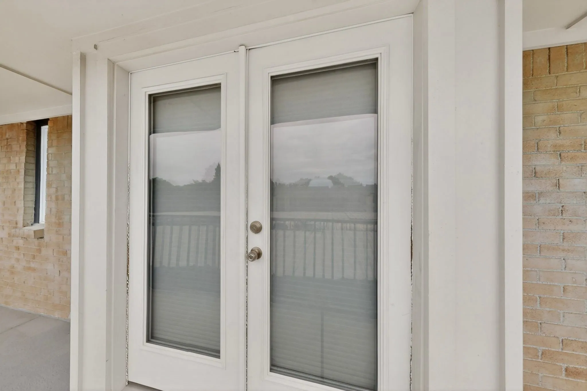 Double French doors with integrated blinds, individual glass panes, and brushed nickel hardware