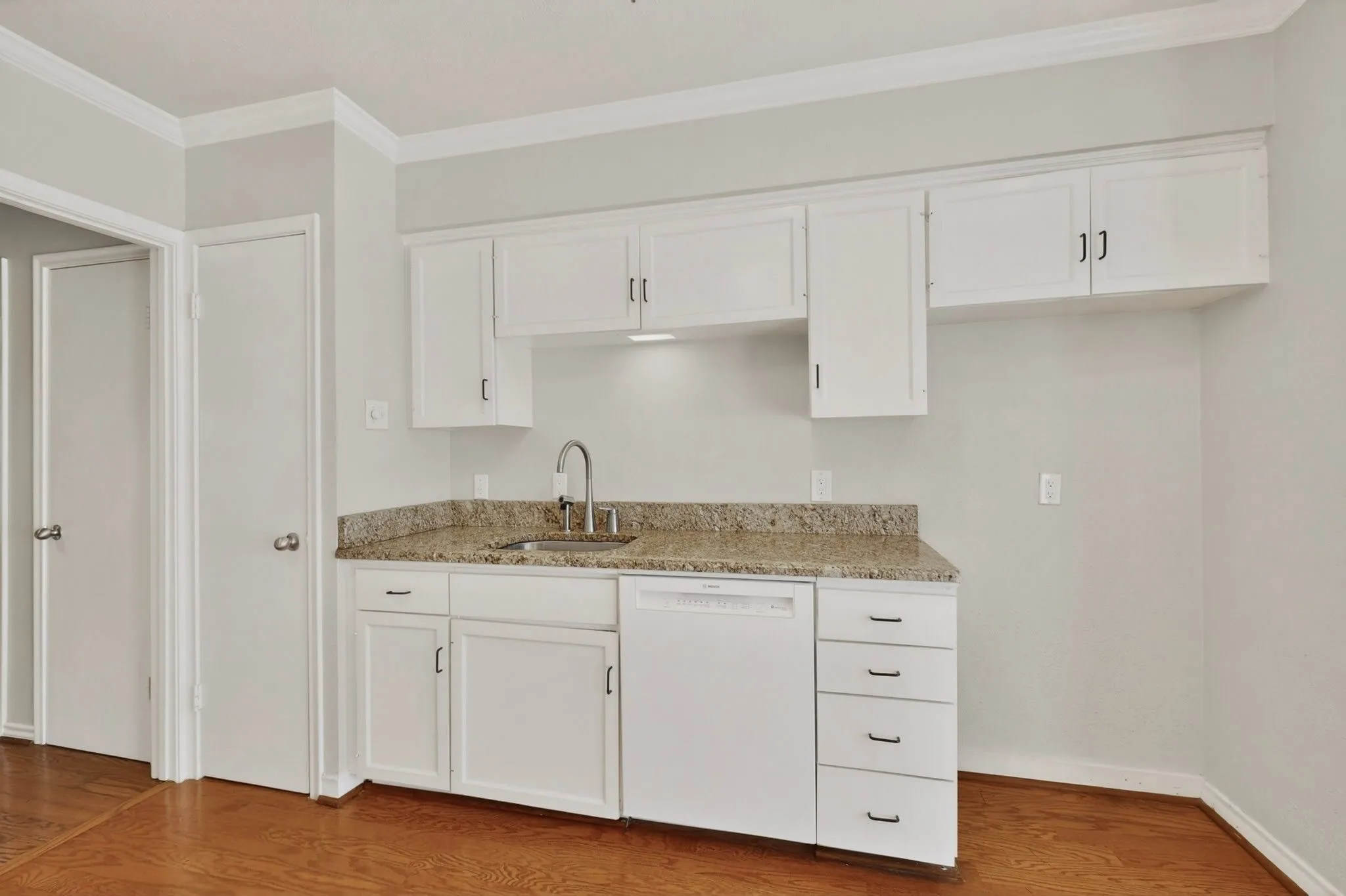 Kitchenette featuring white cabinetry, a stainless steel sink with a high-arc faucet, and granite countertops
