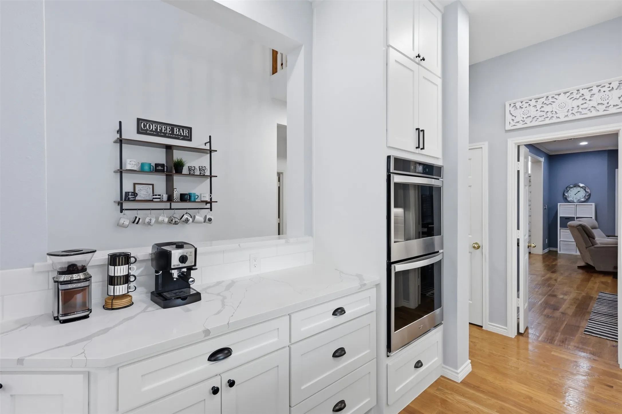 Kitchen featuring white cabinetry with dark hardware, stone-finish countertops, subway tile backsplash, and built-in stainless steel double ovens