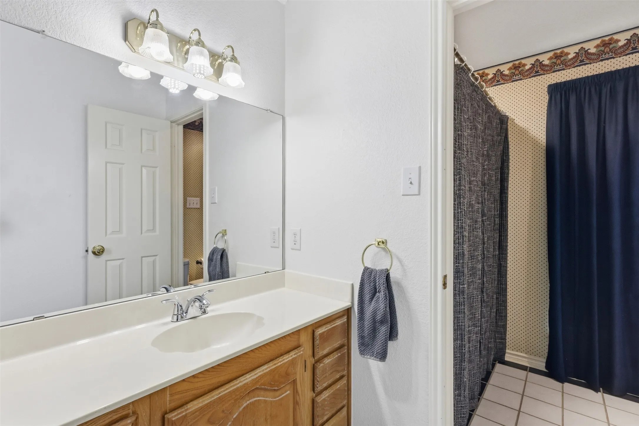 Bathroom vanity with wood-finish cabinetry, a white countertop, and an integrated sink with a chrome faucet
