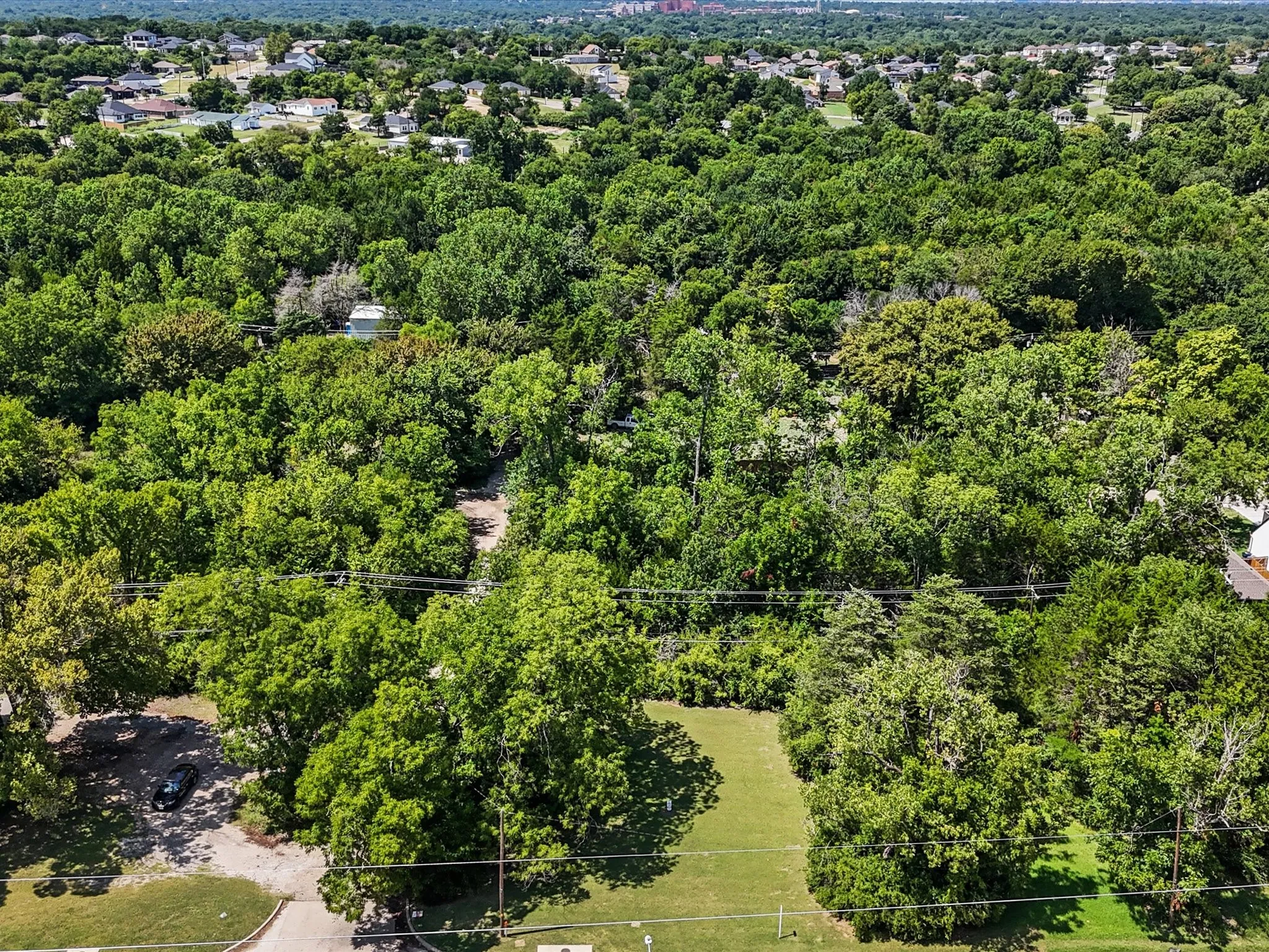 Expansive aerial showcasing a densely wooded lot with significant tree coverage