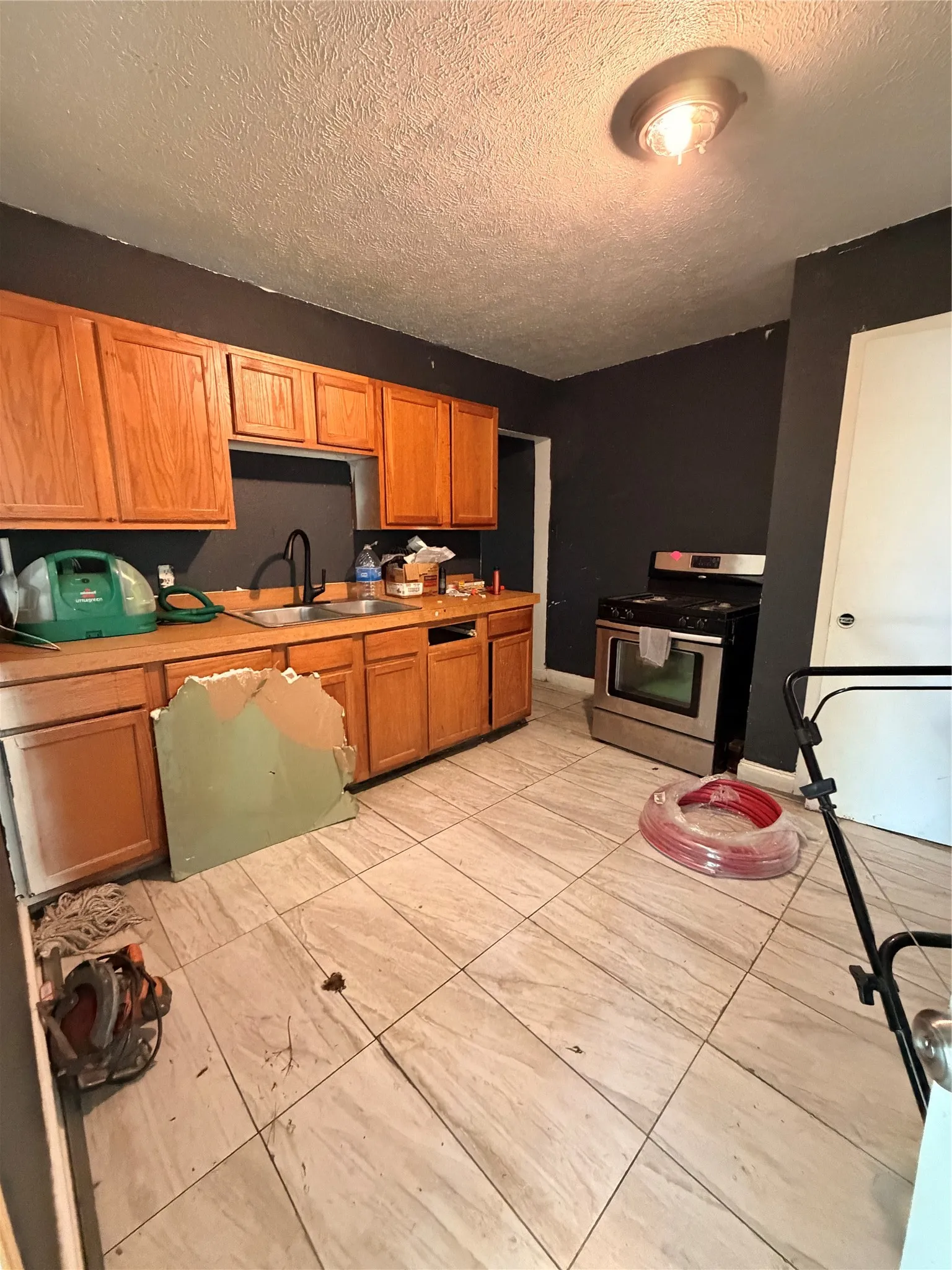 Kitchen featuring wood cabinetry, stainless steel range, and light-toned tile flooring