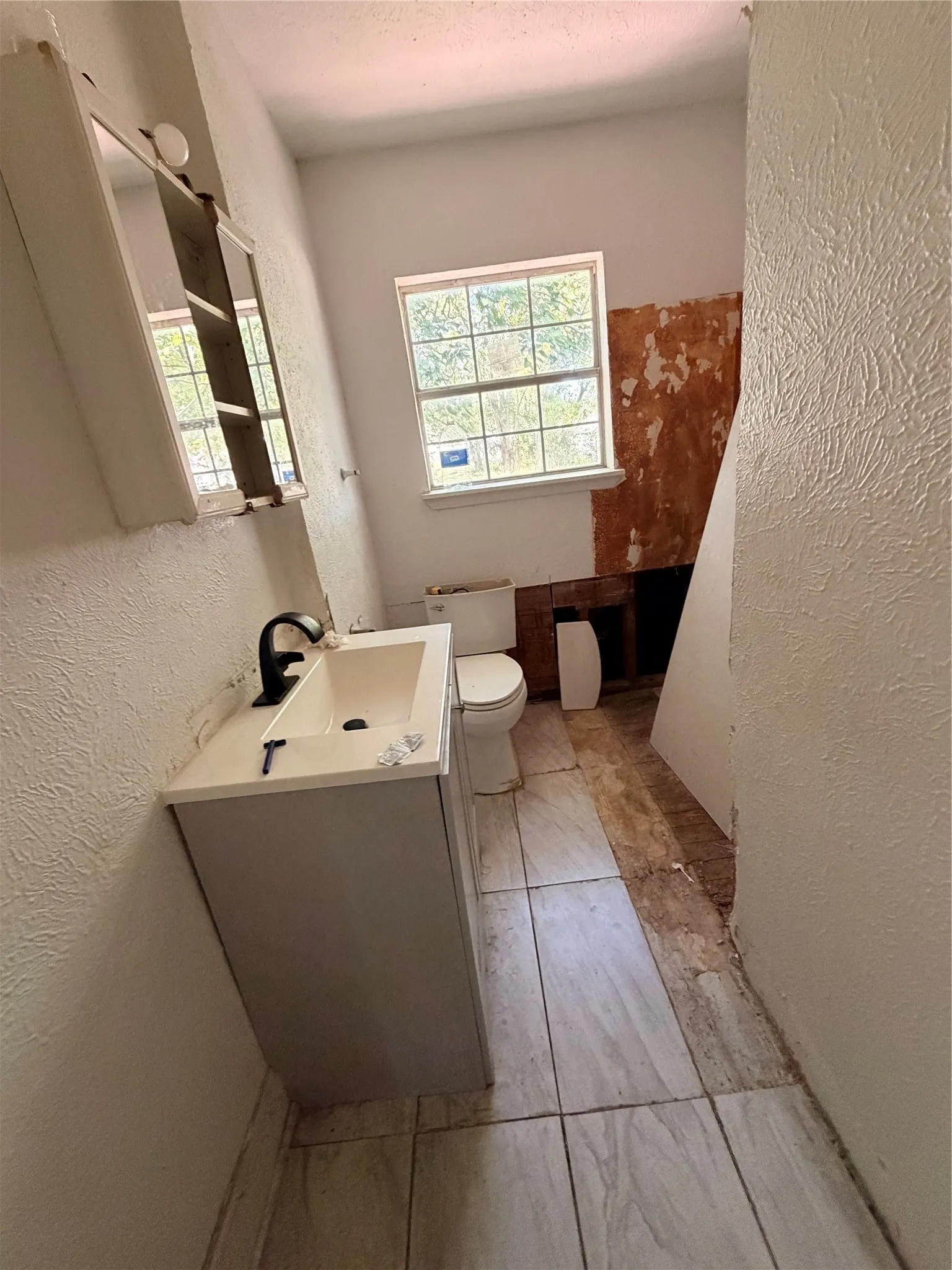 White vanity with integrated sink and matte black faucet, featuring a wall-mounted mirror cabinet