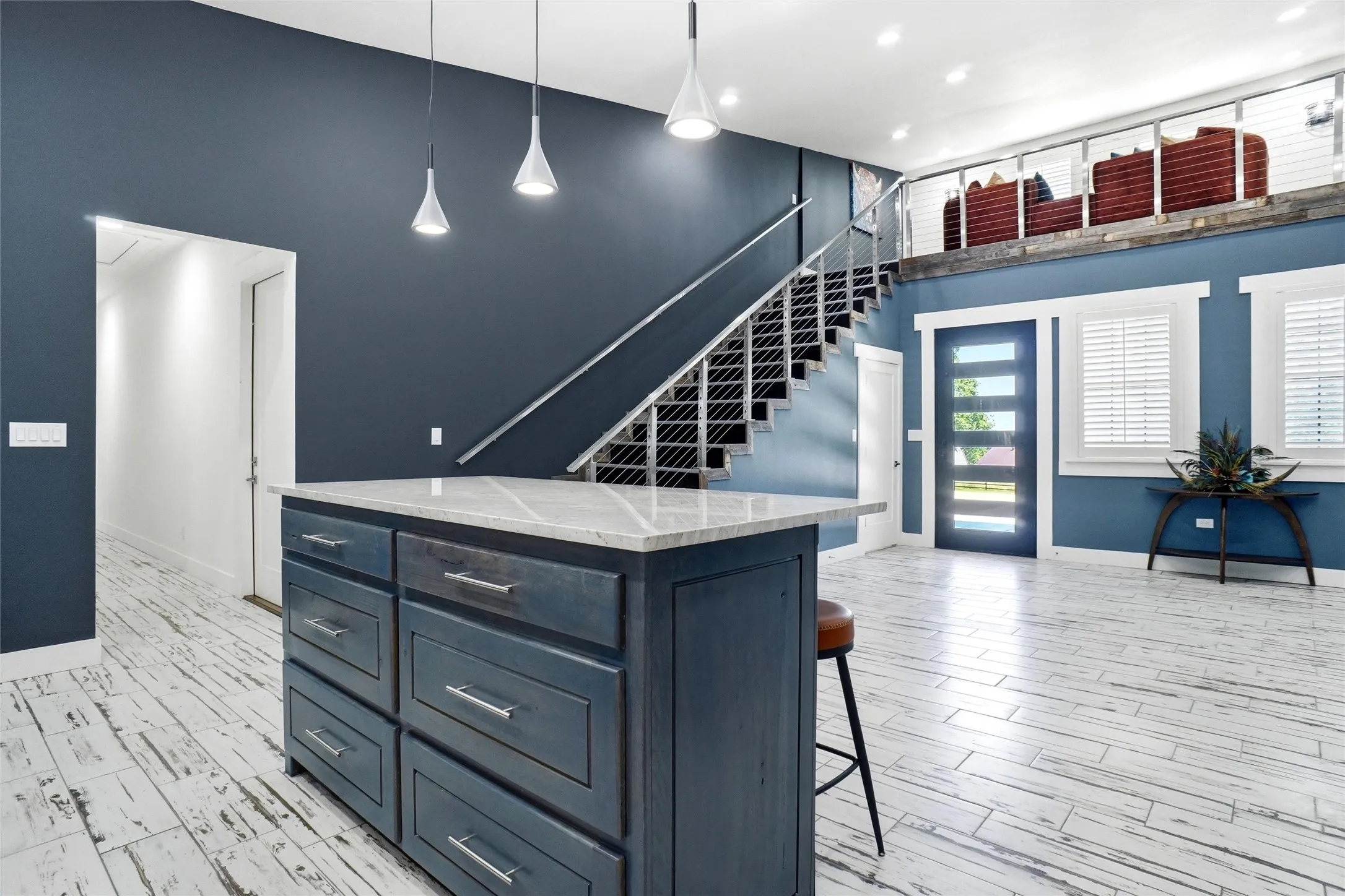 View from kitchen to front door and loft above. Hallway to left of photo leads to fourth bedroom, utility room and half bath.