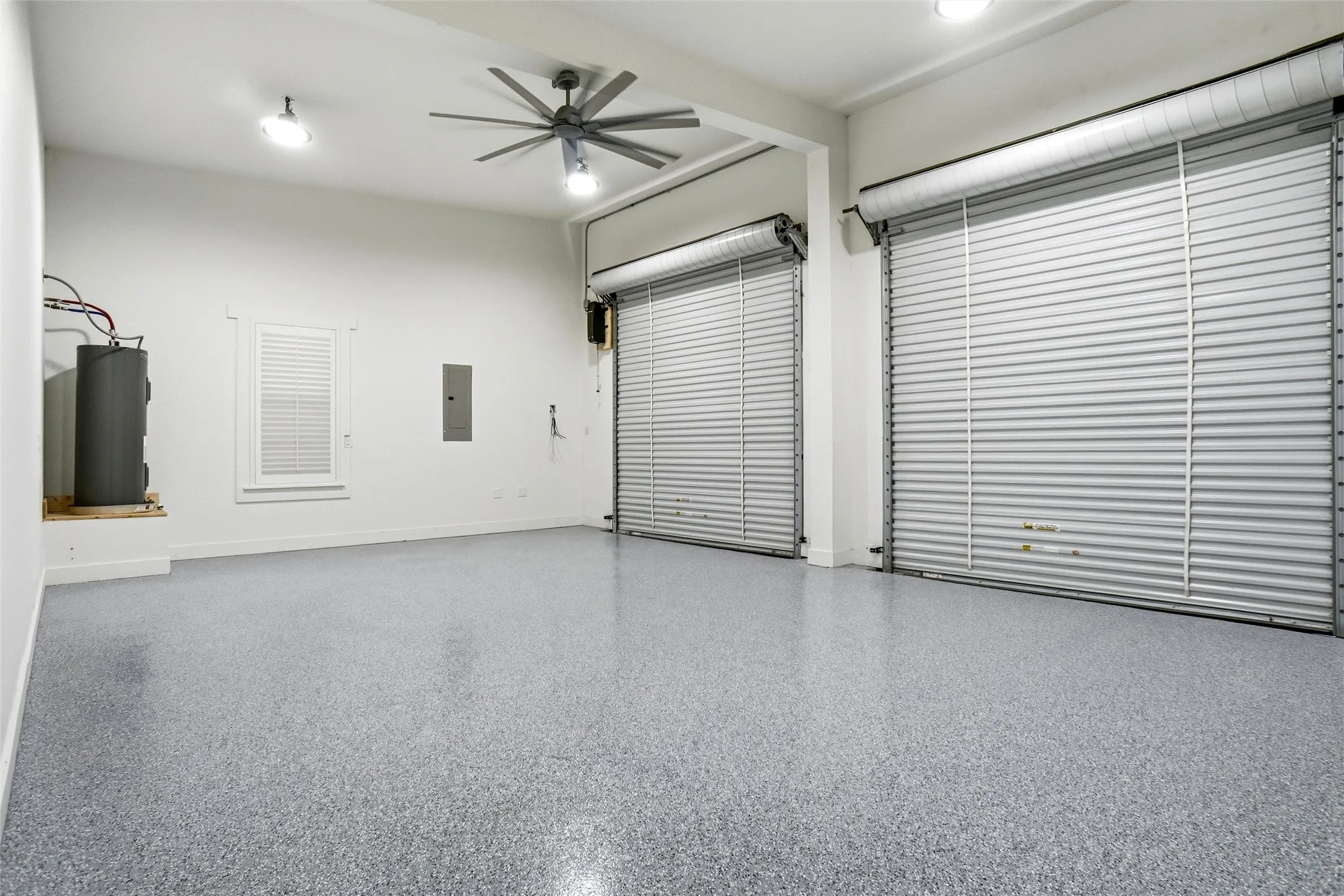 Garage at main house with oversized roll-up doors and ceiling fan.