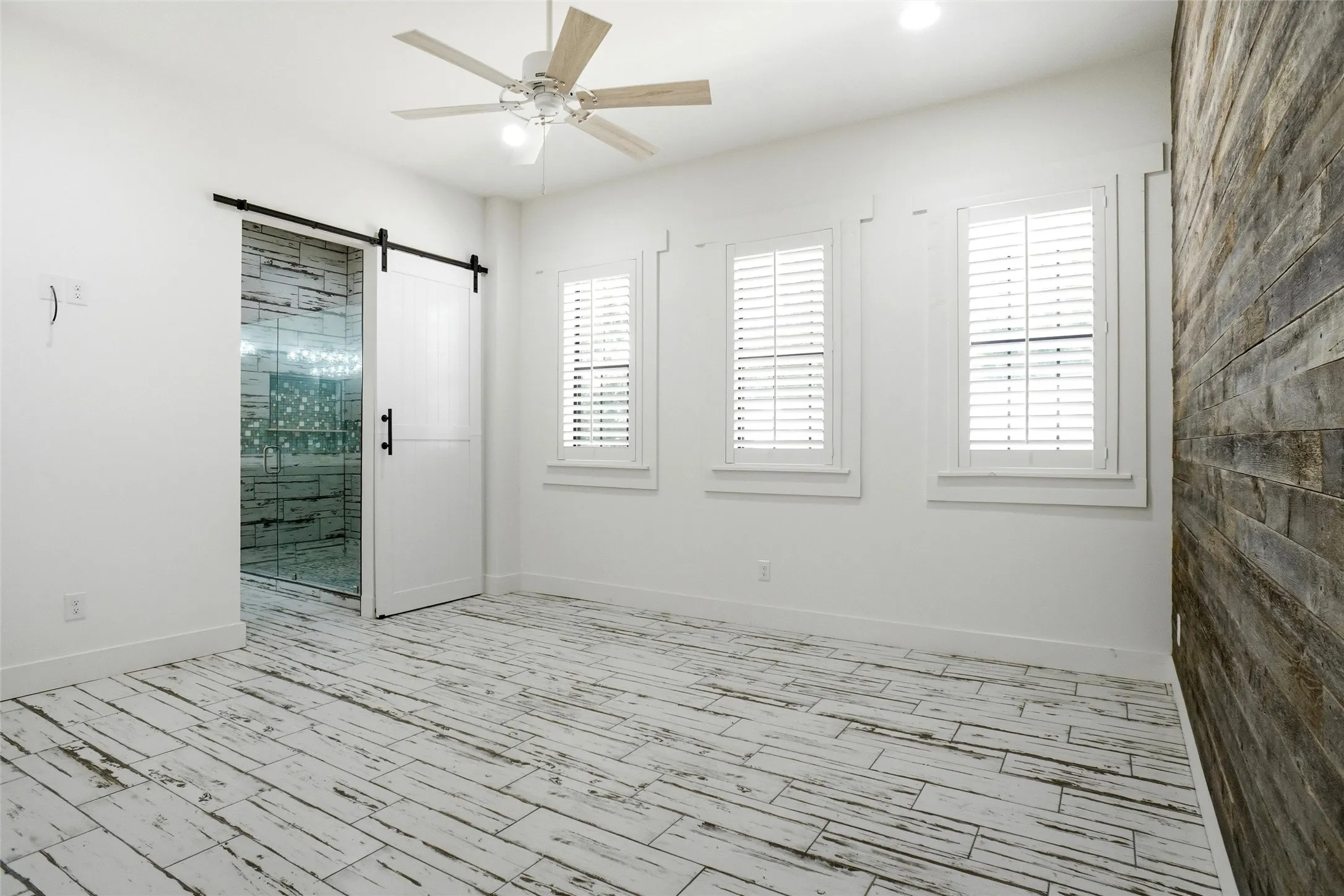 Primary bedroom with accent wall; ensuite bath visible beyond. Plantation shutters throughout!