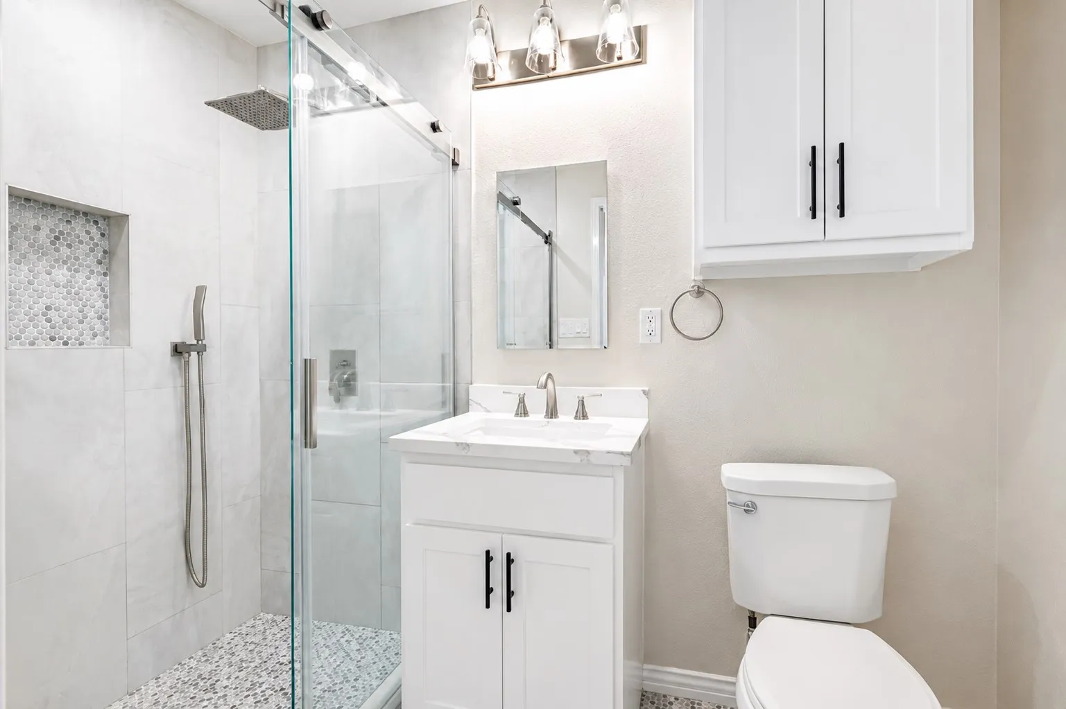 Modern bathroom featuring a glass-enclosed shower with a rainfall showerhead and a tiled niche