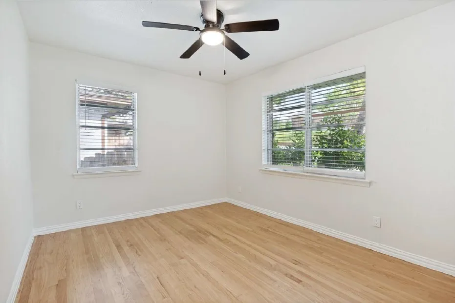 3rd Bedroom featuring light wood-finish flooring complemented by white baseboards, a ceiling fan with integrated lighting, and dual windows featuring horizontal blinds