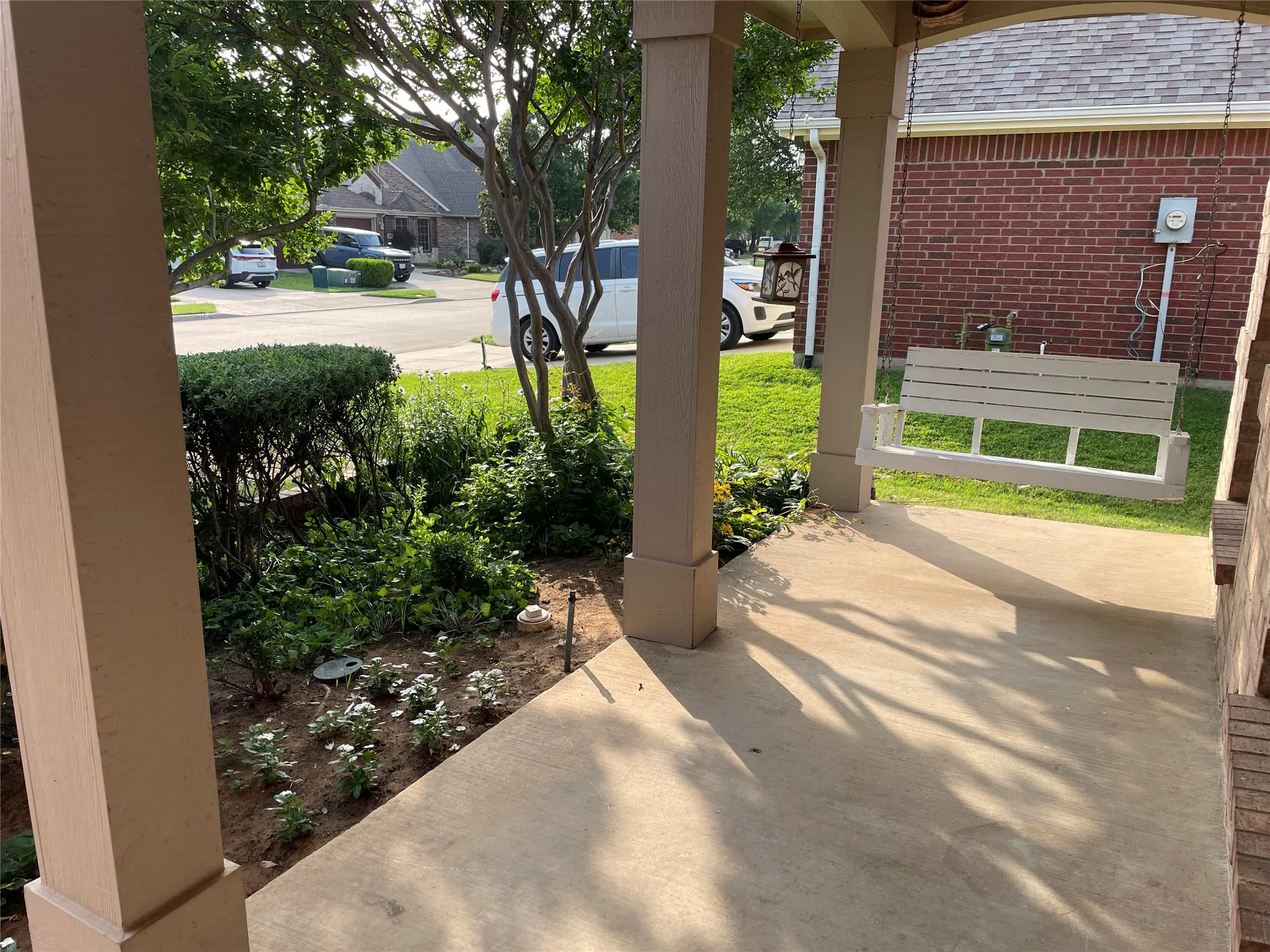 Front porch with swing and blooming beds
