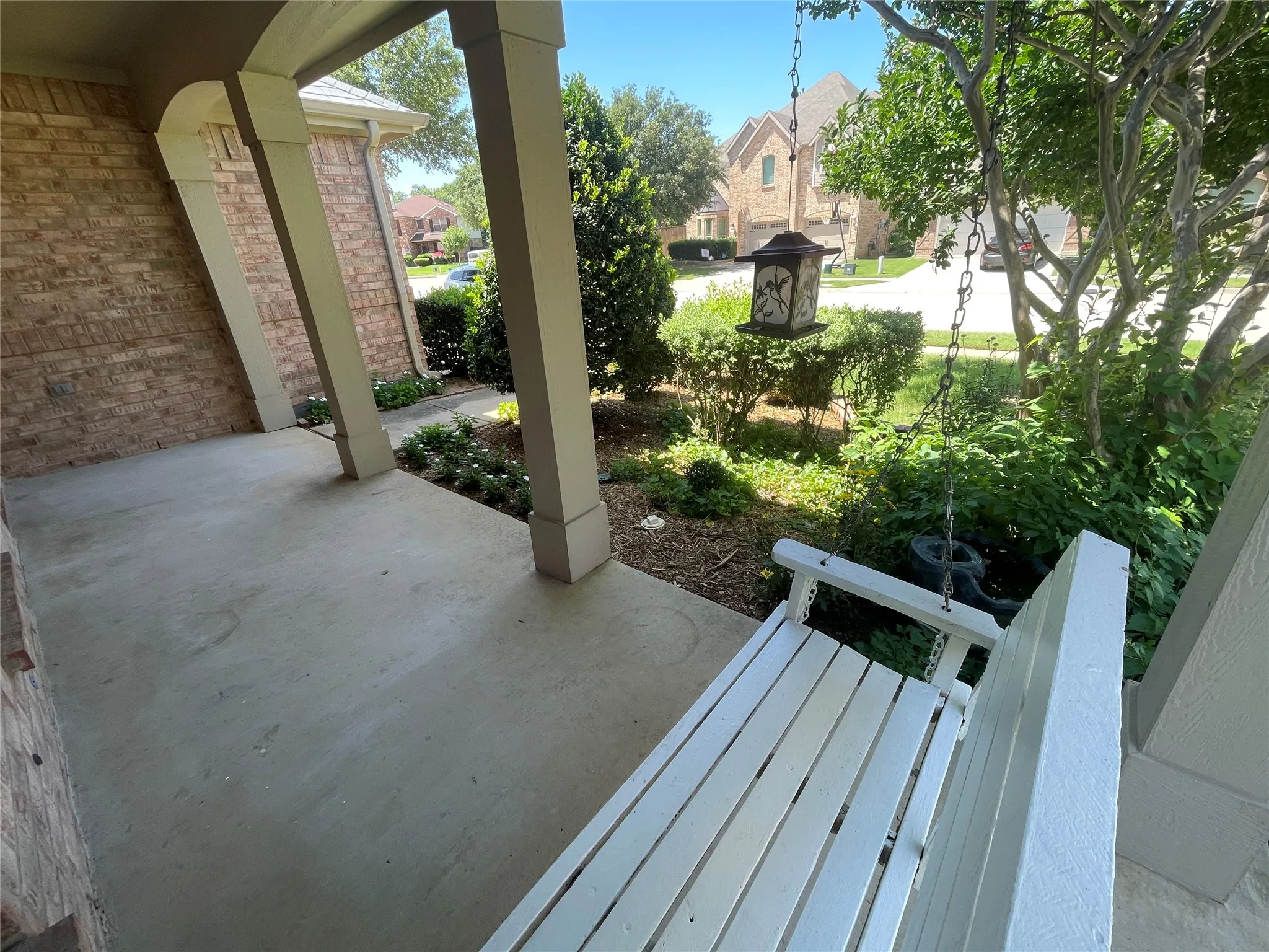 Front porch swing offers shady relaxation near pretty flower beds.
