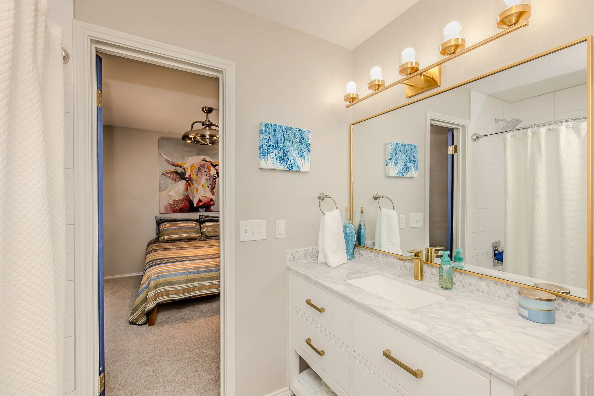 Bathroom vanity featuring a white rectangular undermount sink set in a light-toned countertop, complete with a gold-tone faucet and matching hardware