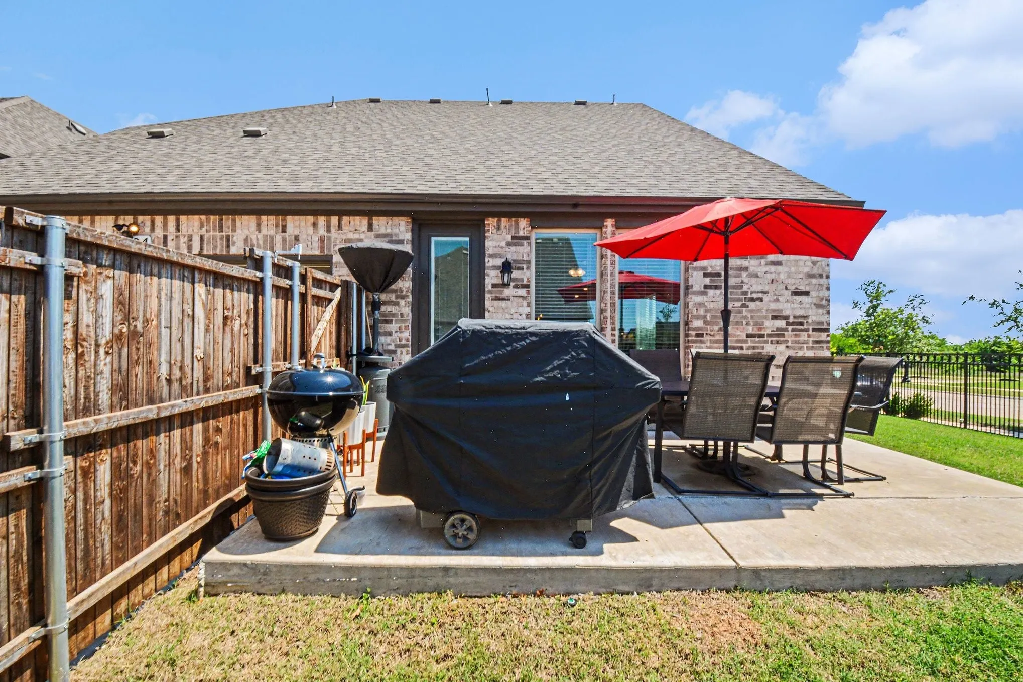 Expansive outdoor patio area featuring a concrete slab, brick exterior, and a privacy fence