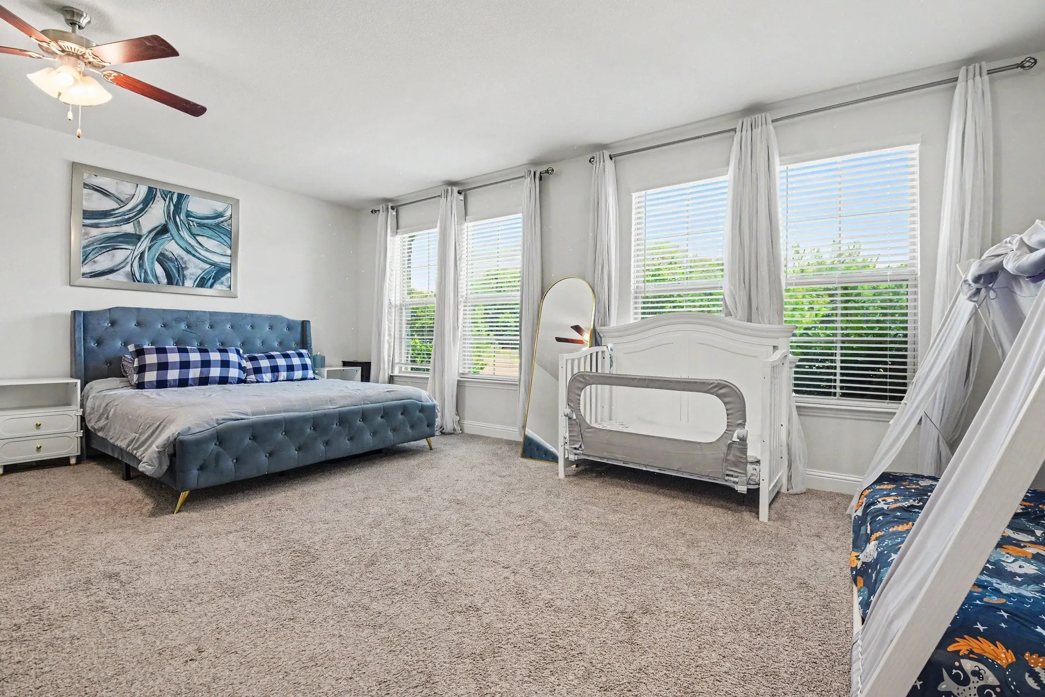 Carpeted room featuring multiple windows with blinds, a ceiling fan, and white walls