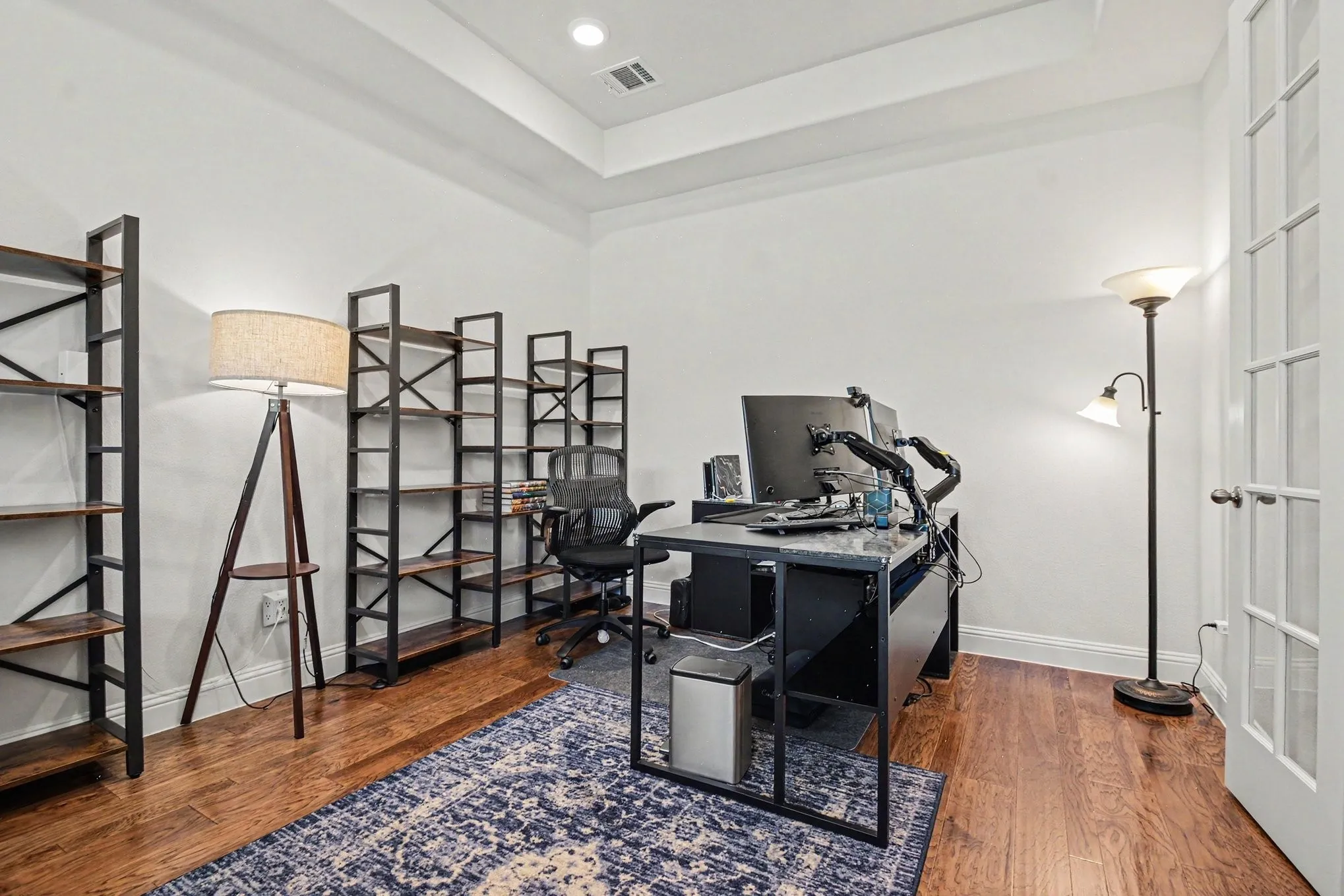 Dedicated room featuring wood-finish flooring, a tray ceiling, and white walls