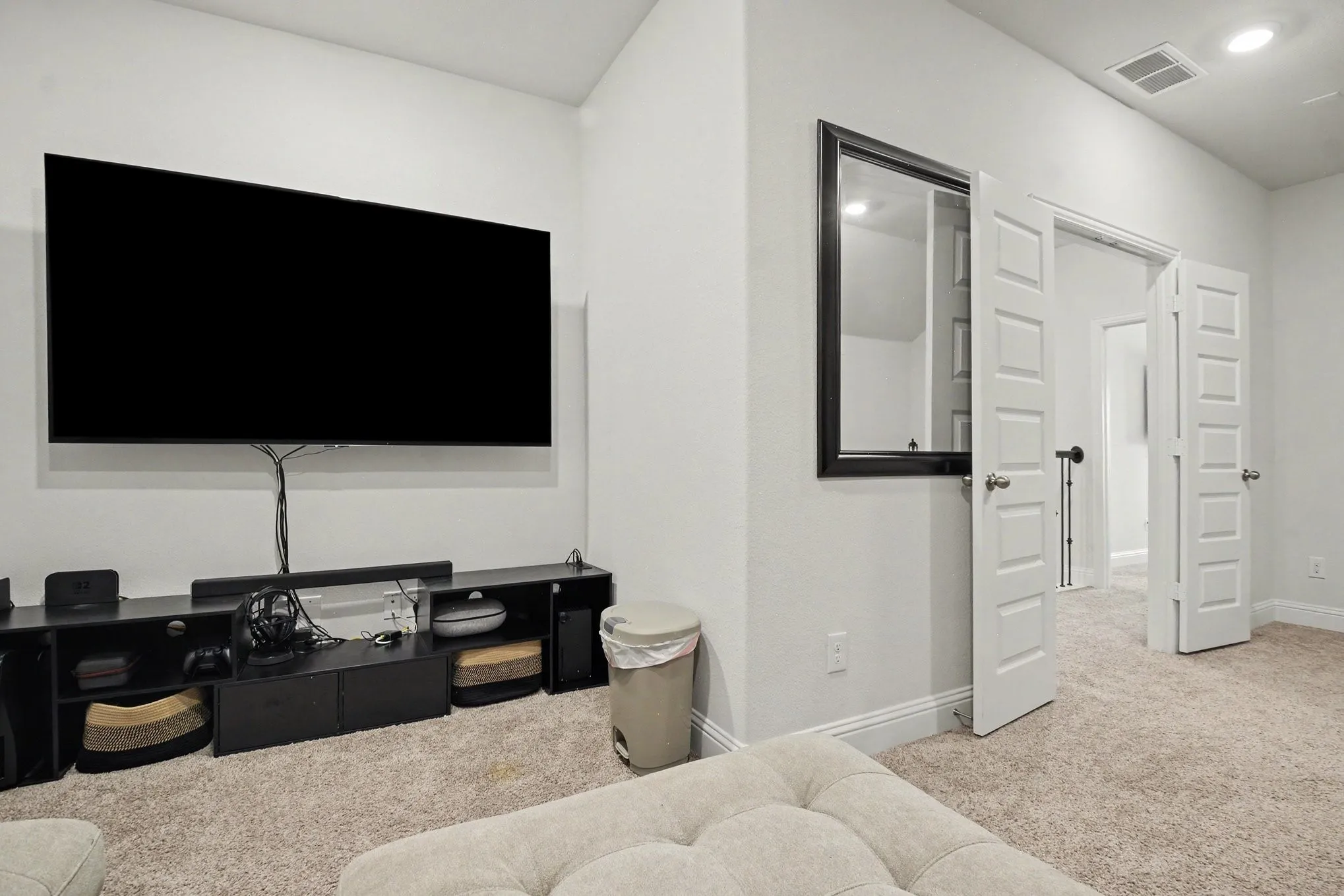 Carpeted room featuring a wall-mounted television, a black media console, and white paneled double doors