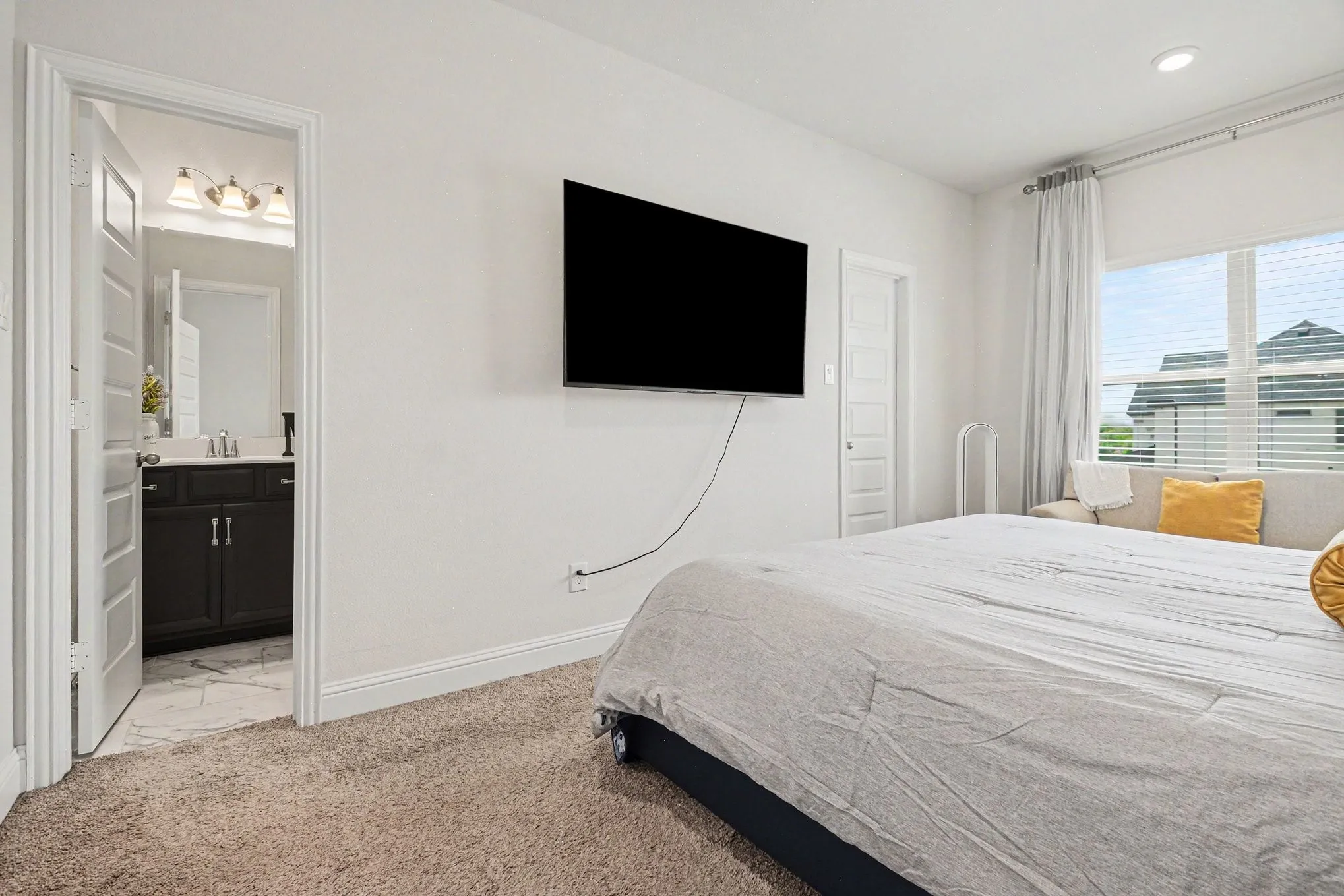 Plush carpeted flooring and white wall finishes in a spacious room featuring a large window with horizontal blinds and an architectural ceiling detail