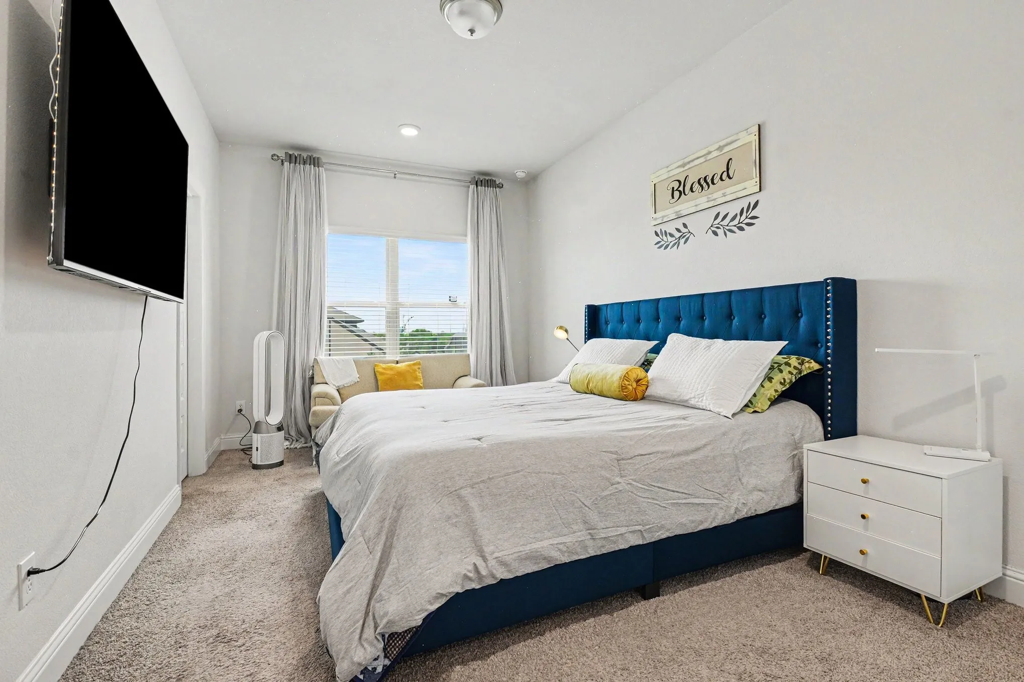 Carpeted bedroom with a window featuring blinds and light-filtering curtains