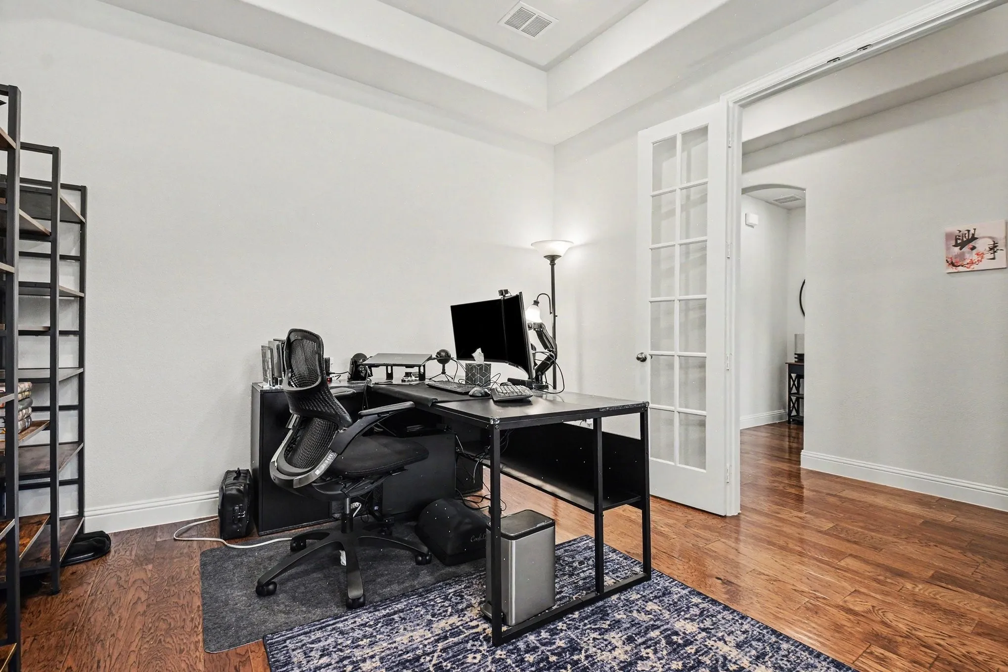 Dedicated room featuring wood-finish flooring, a tray ceiling, and white walls