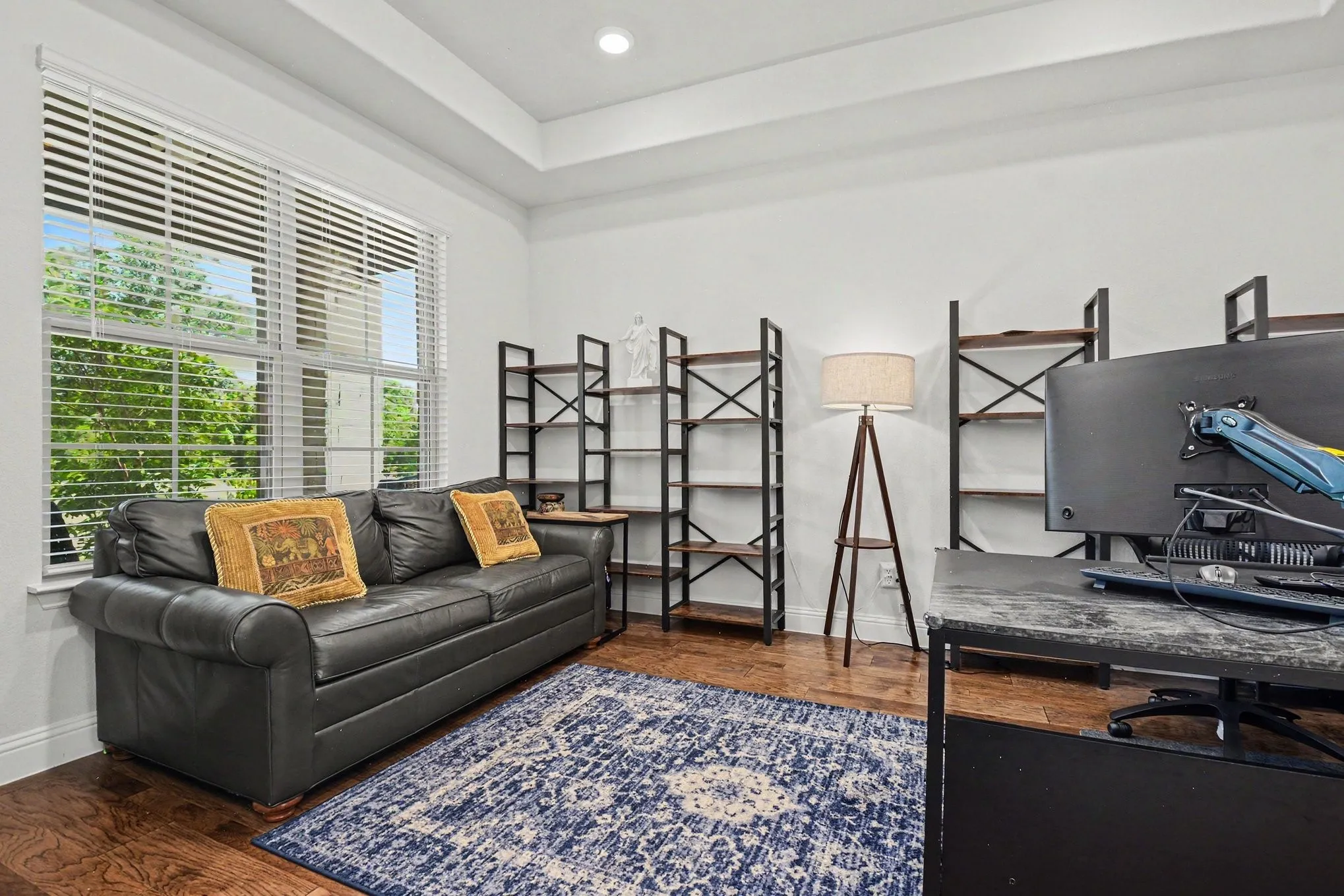 Spacious room featuring wood-finish flooring and a tray ceiling