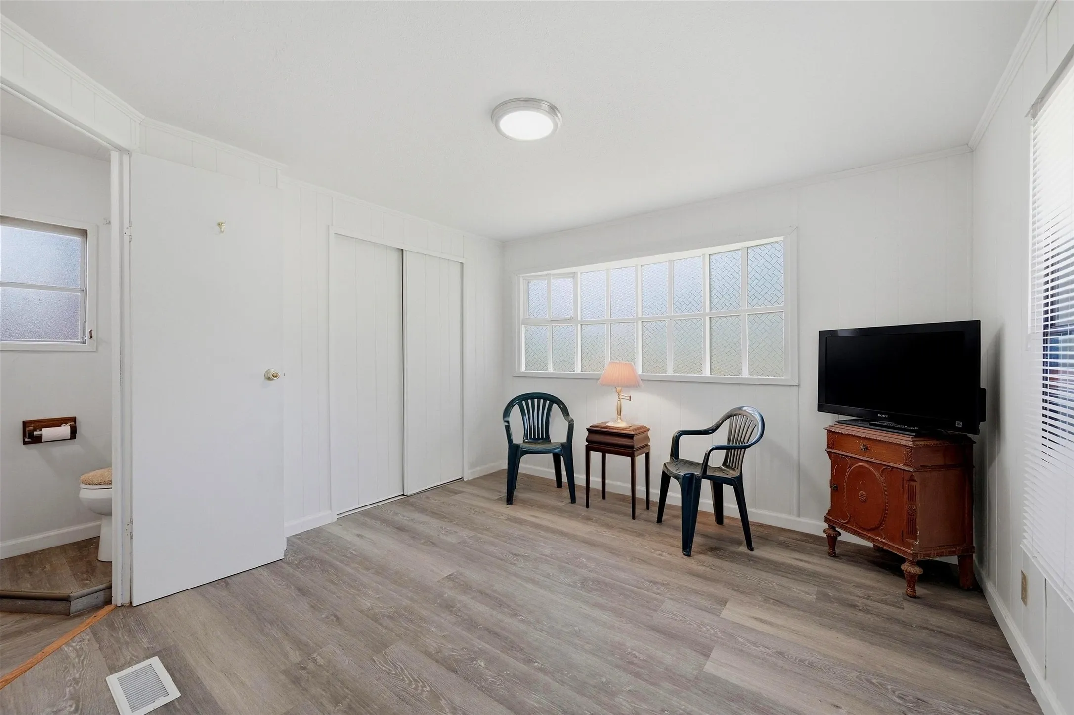 Bright room featuring light wood-finish flooring, white walls, and a window offering natural illumination