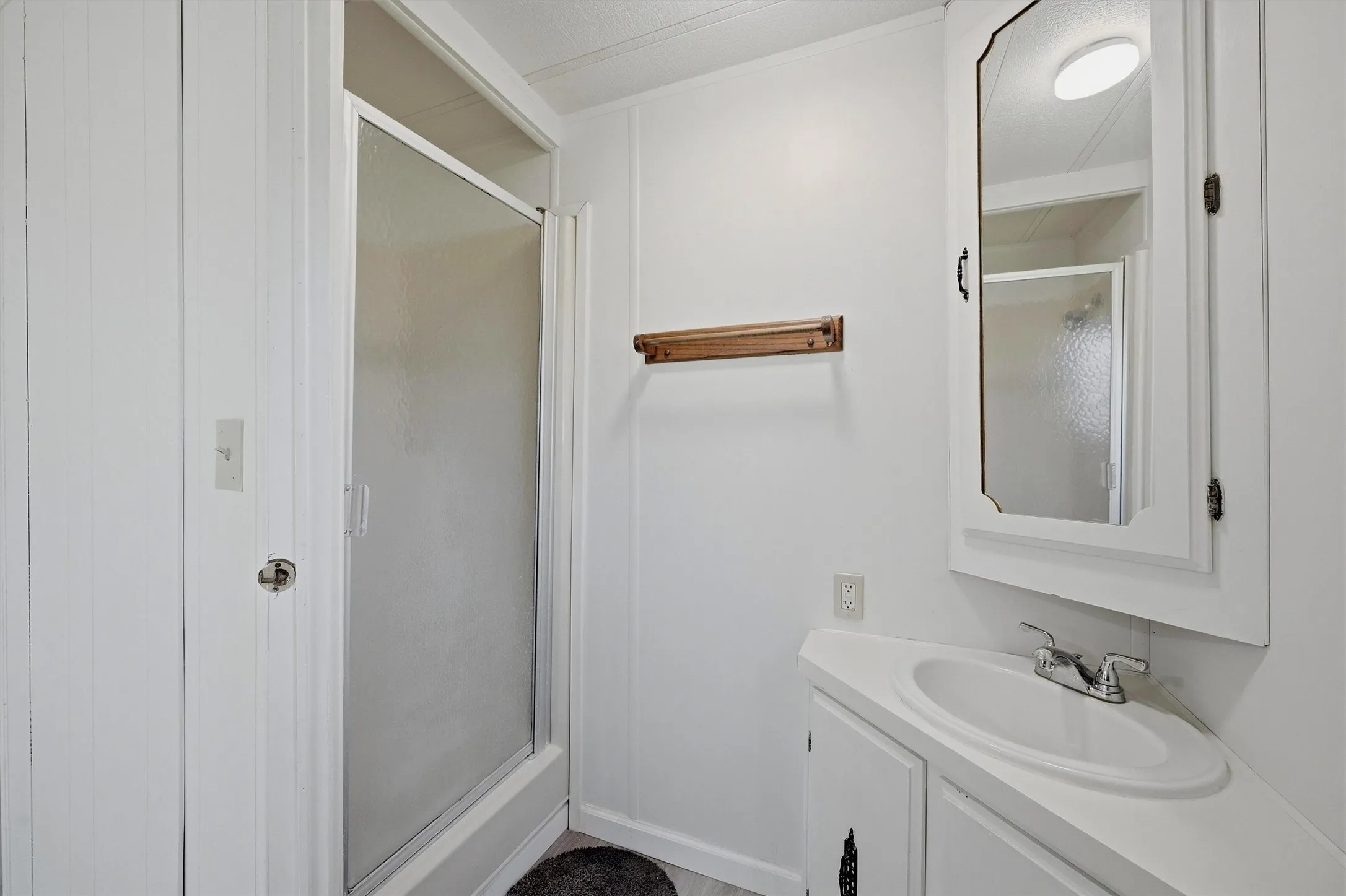 Bathroom featuring a corner vanity with an integrated sink, chrome faucet, and a wall-mounted medicine cabinet with a mirror