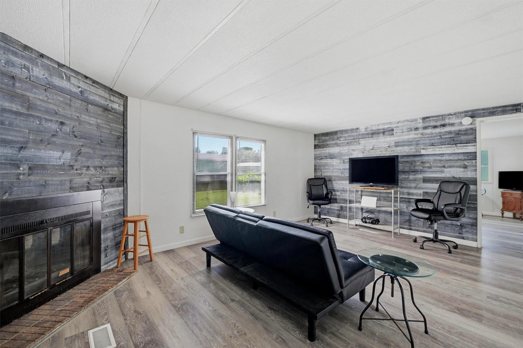 Living room featuring a prominent fireplace with a dark wood-finish accent wall