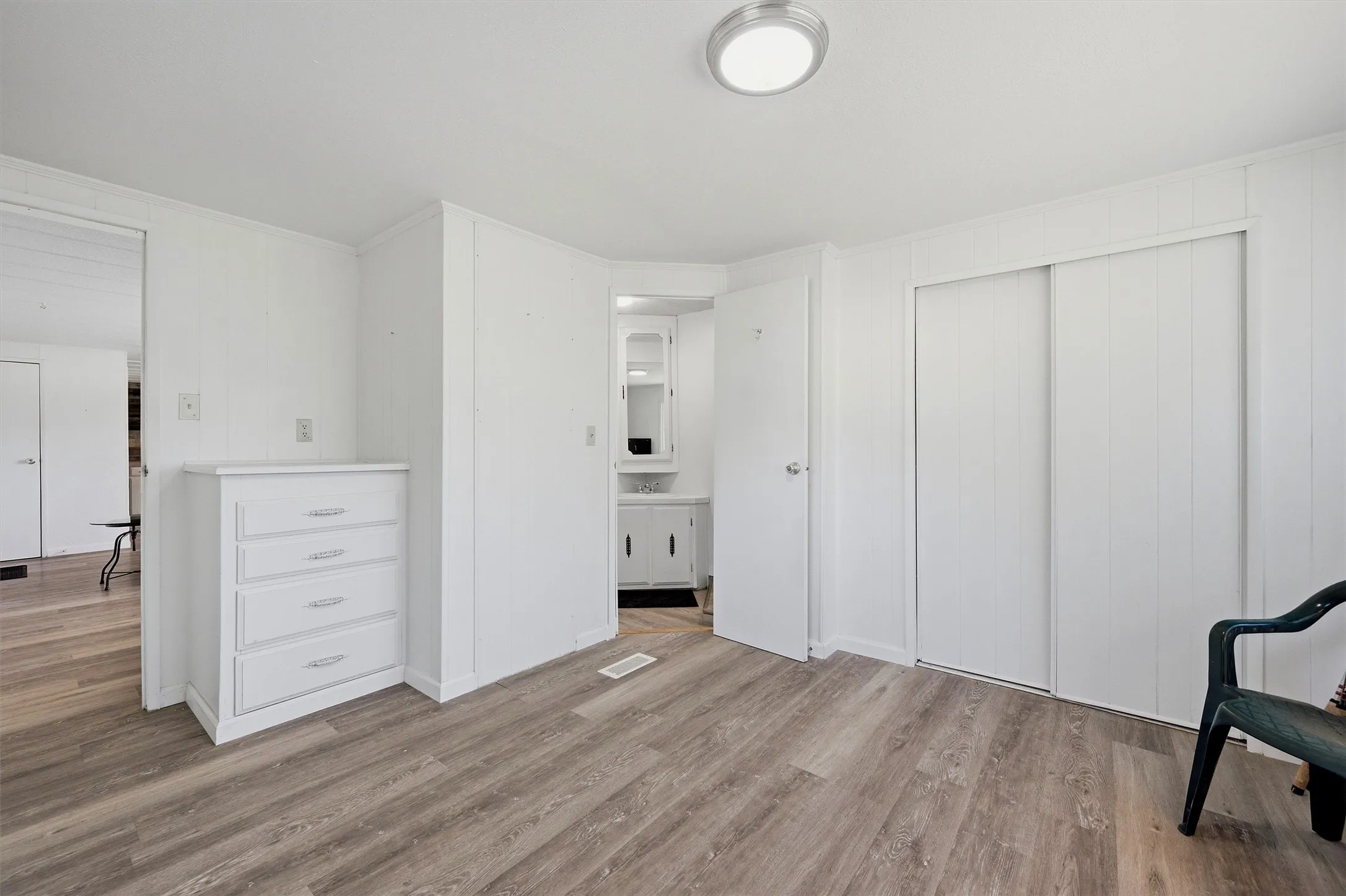 Room featuring wood-finish flooring, white panel walls, and a ceiling-mounted light fixture