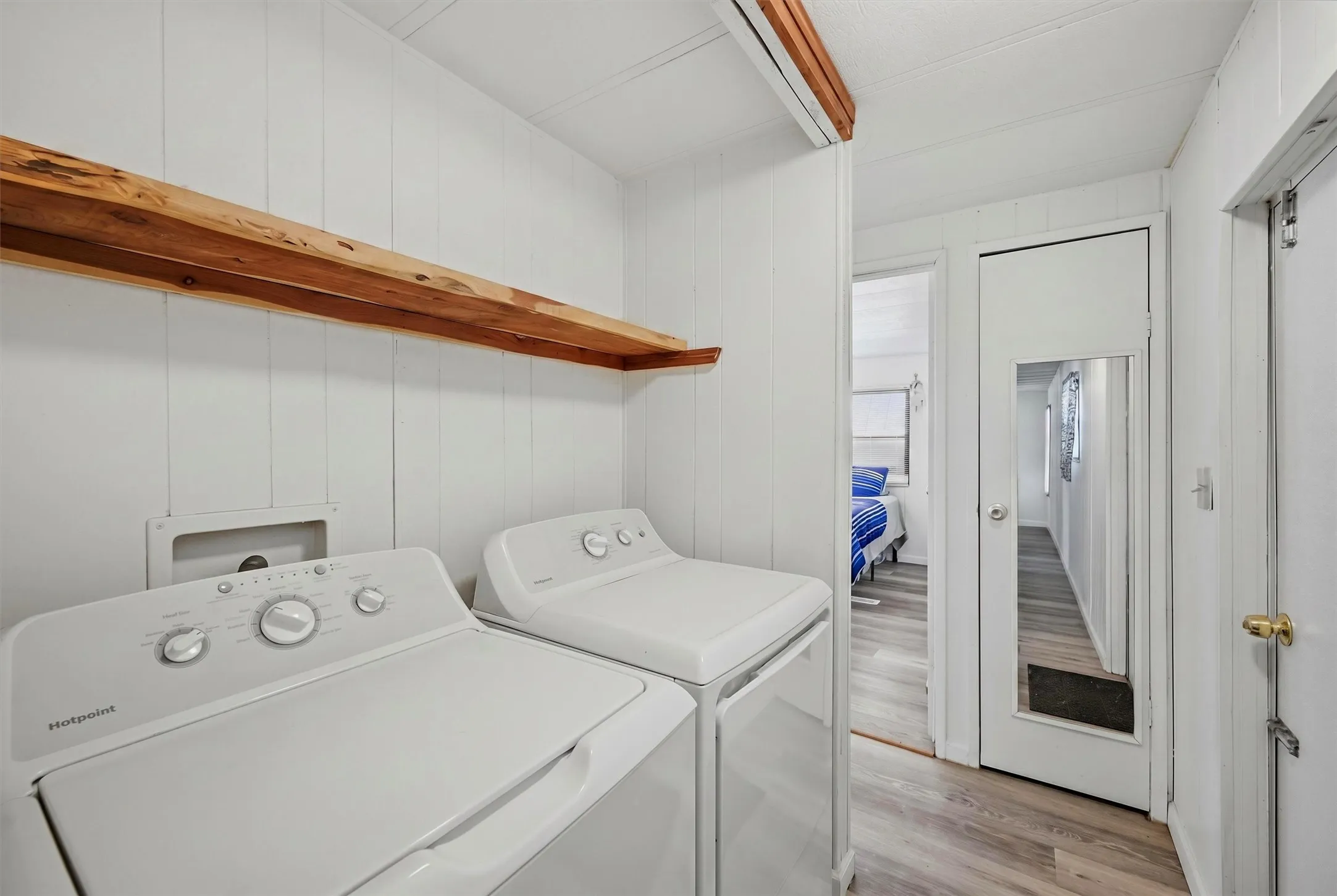 Dedicated laundry area featuring a wood-finish shelf and white paneling