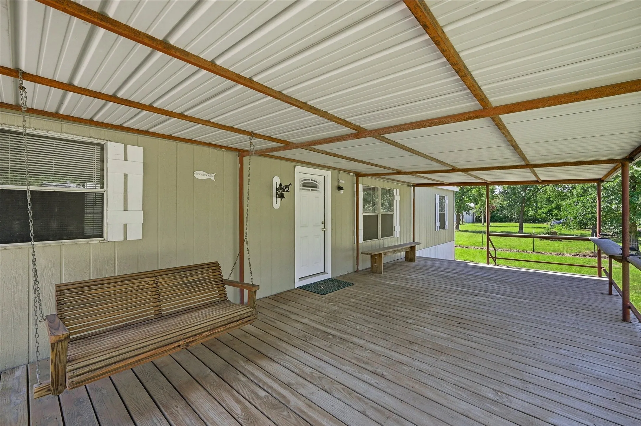 Expansive covered wood deck featuring a white metal roof, exposed structura