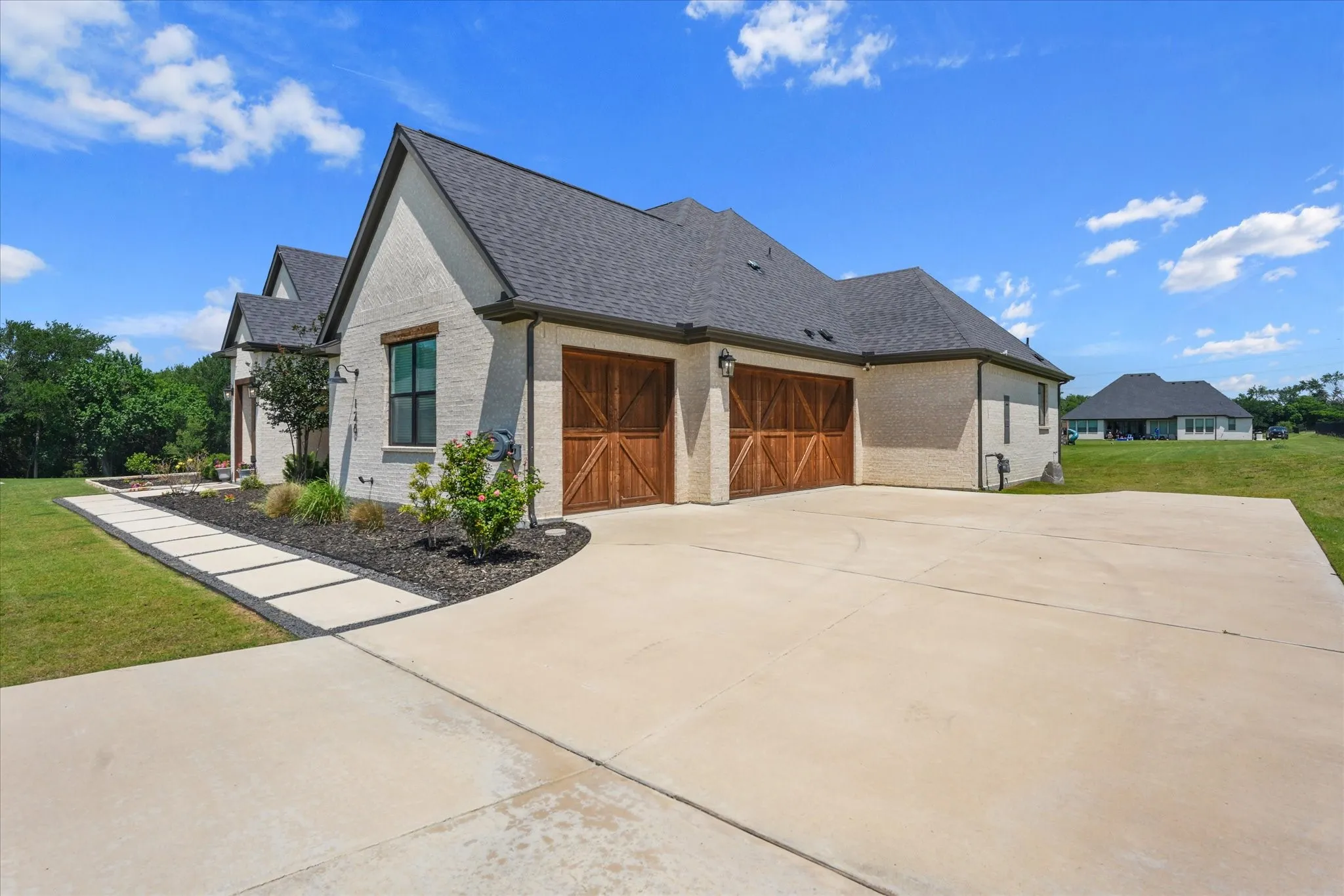 Exterior architectural details include a painted brick facade, dark roofing, and a prominent attached three-car garage with wood-finish doors