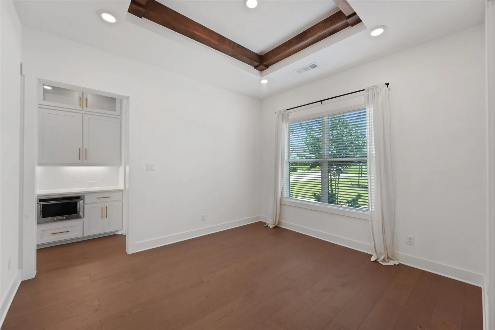 Recessed lighting illuminating a spacious room with wood-finish flooring